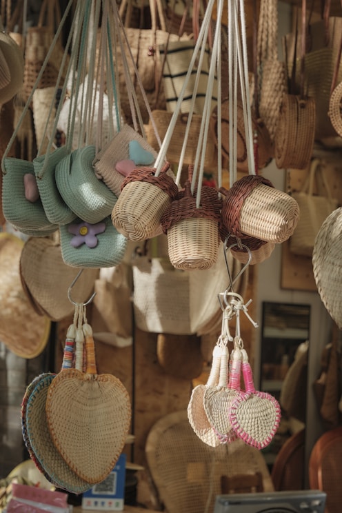 Woven bags and heart-shaped fans hanging at a market.