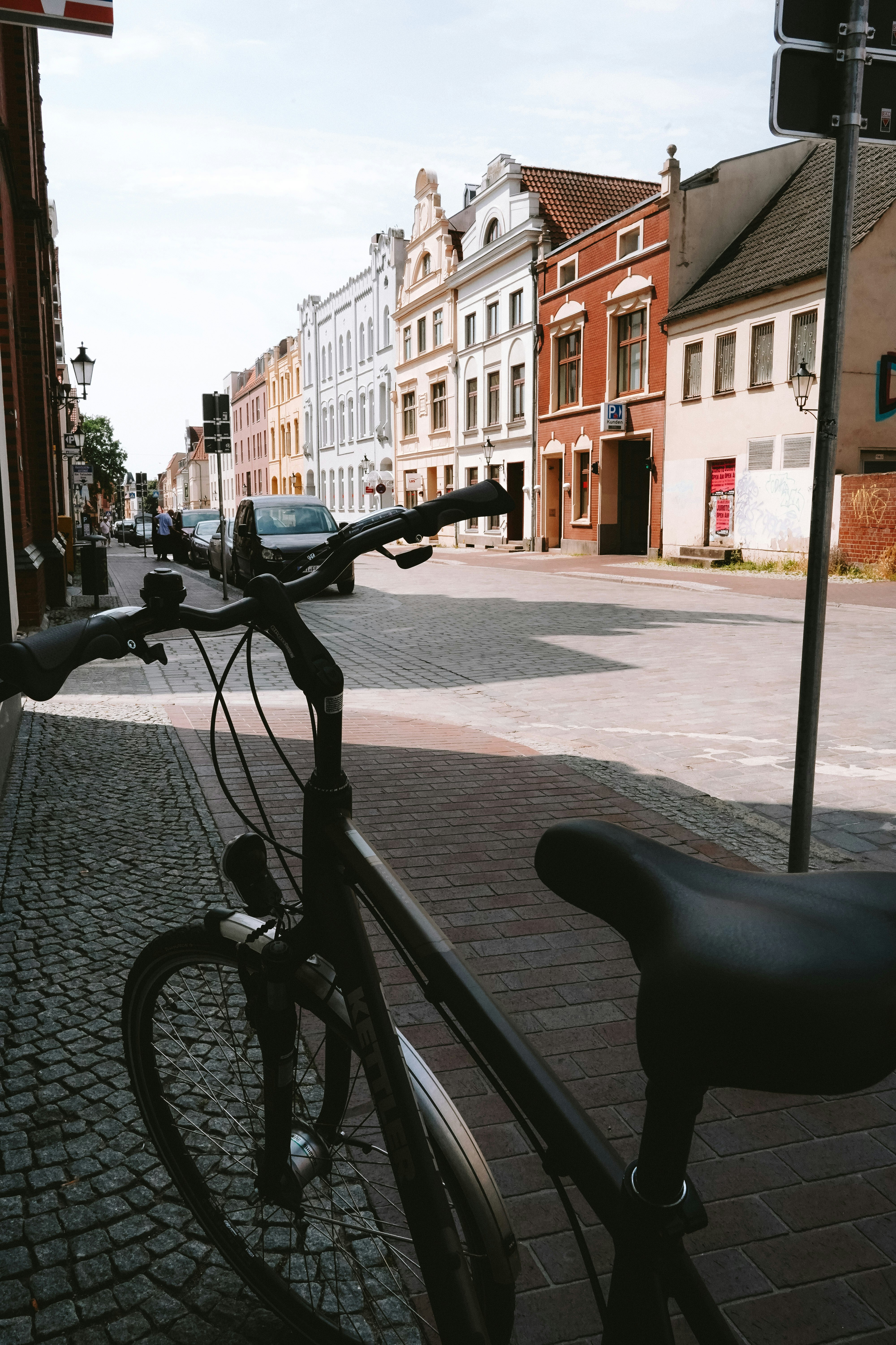 Bicycle parked on a cobblestone street in town.