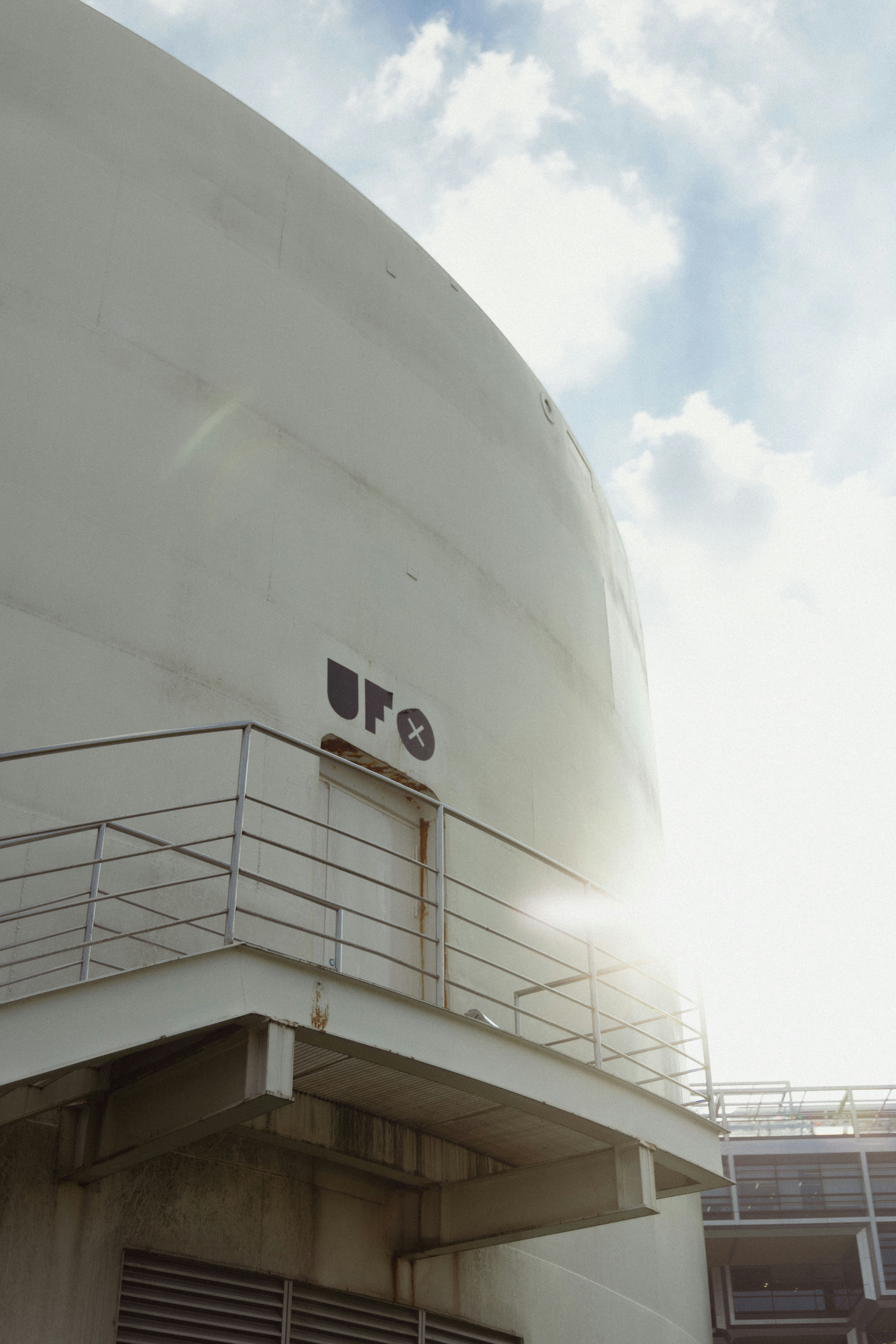 White cylindrical building with ufo sign and sun flare