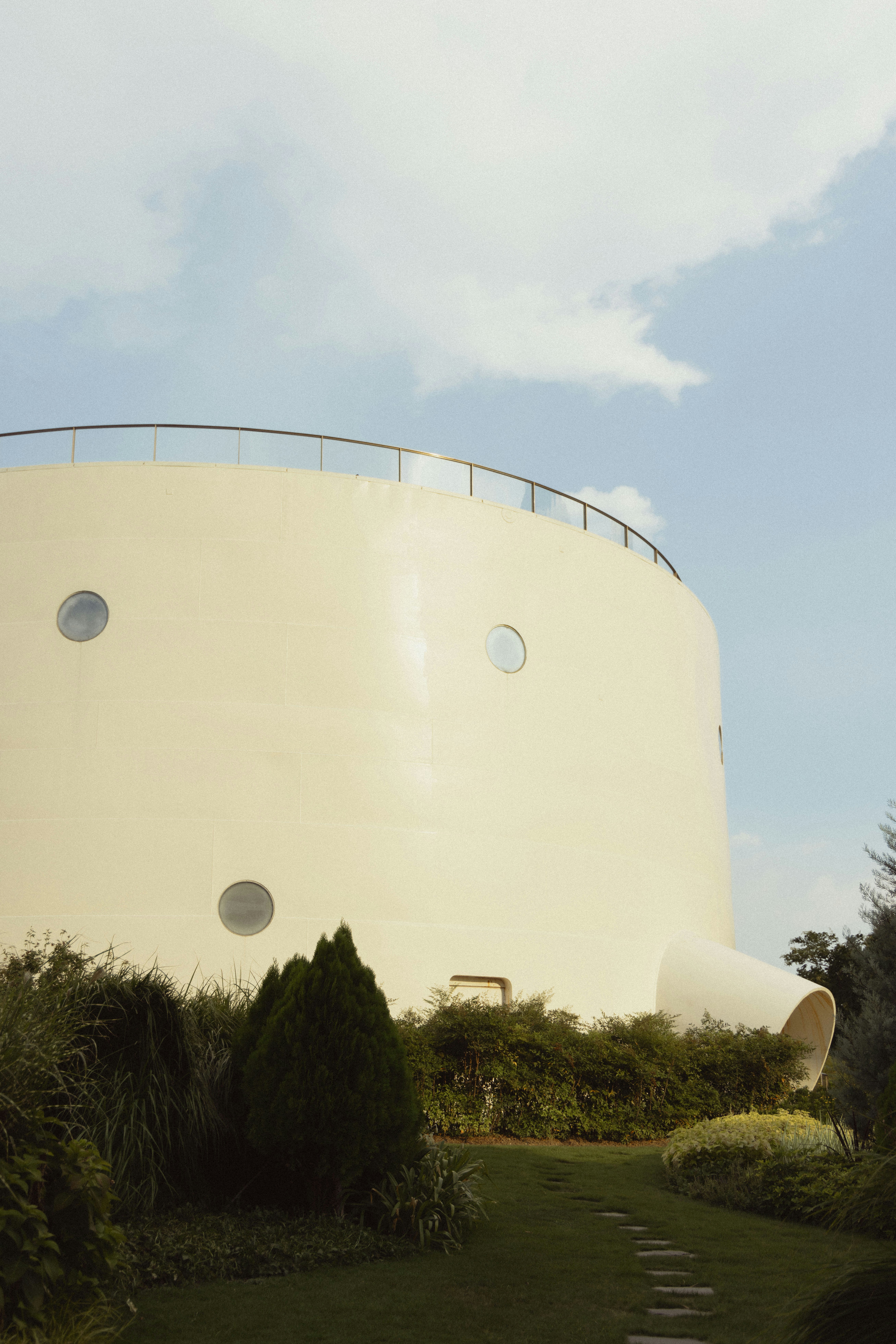 Curved building with round windows and lush greenery