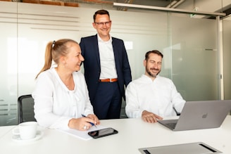 Three colleagues collaborating around a laptop in an office.