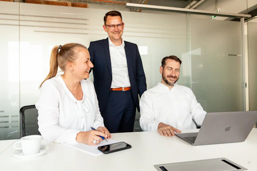 Three colleagues collaborating around a laptop in an office
