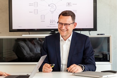 Man in suit smiling in front of a diagram