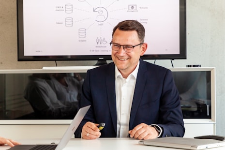 Man in suit smiling in front of a diagram