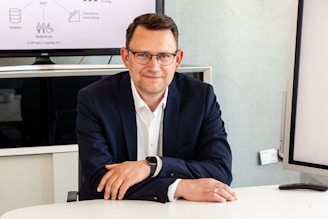 Man in suit and glasses sits at table