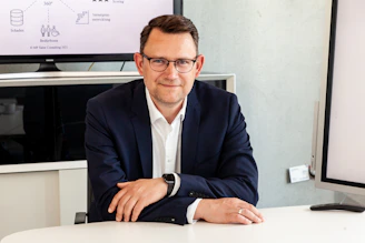 Man in suit and glasses sits at table