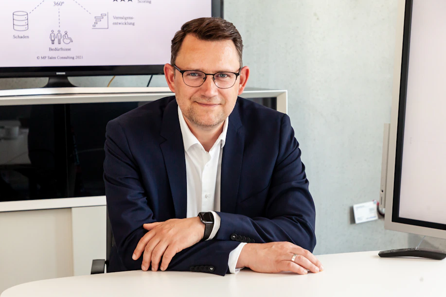 Man in suit and glasses sits at table