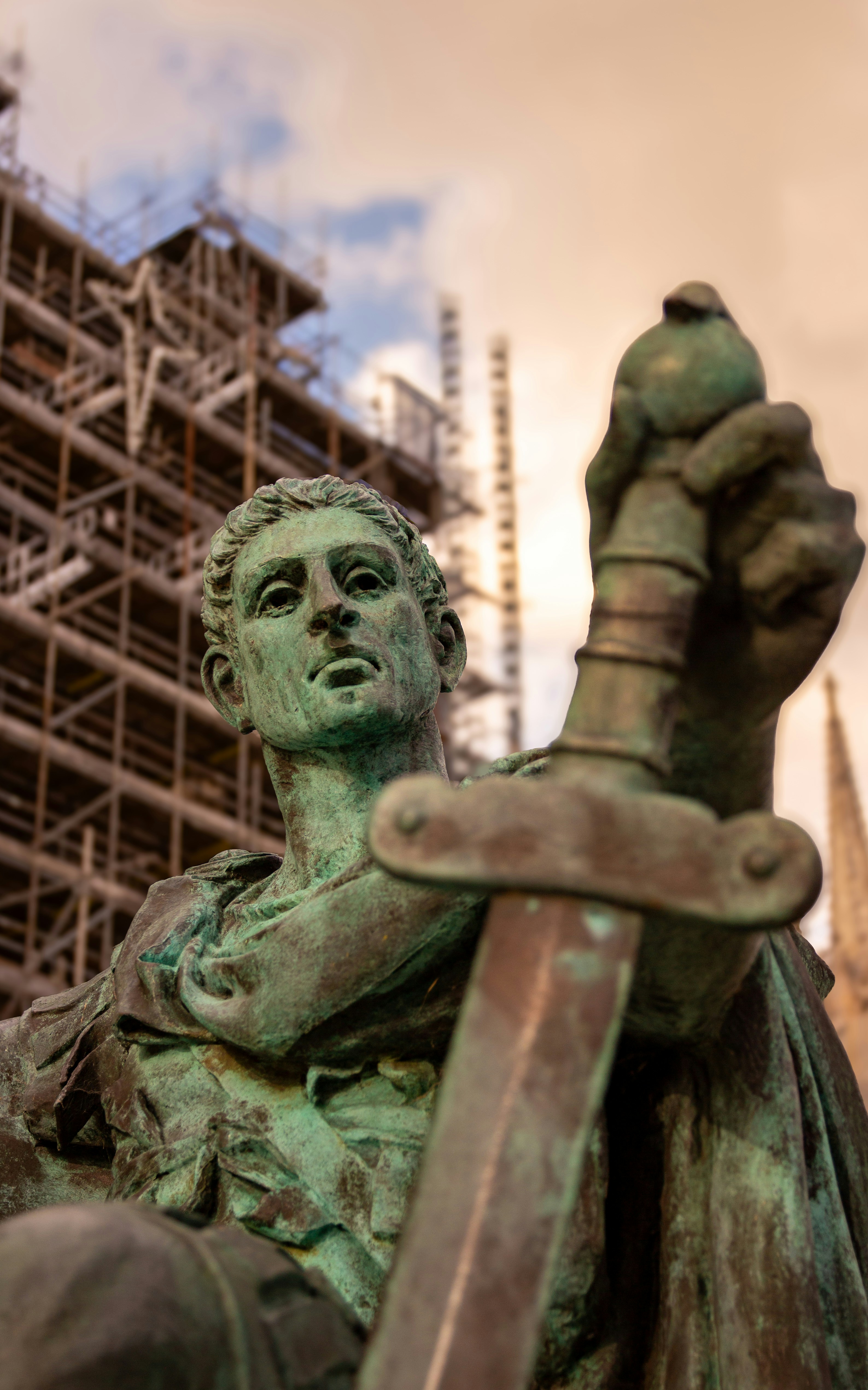 Estatua de bronce de un hombre sosteniendo una espada al aire libre.