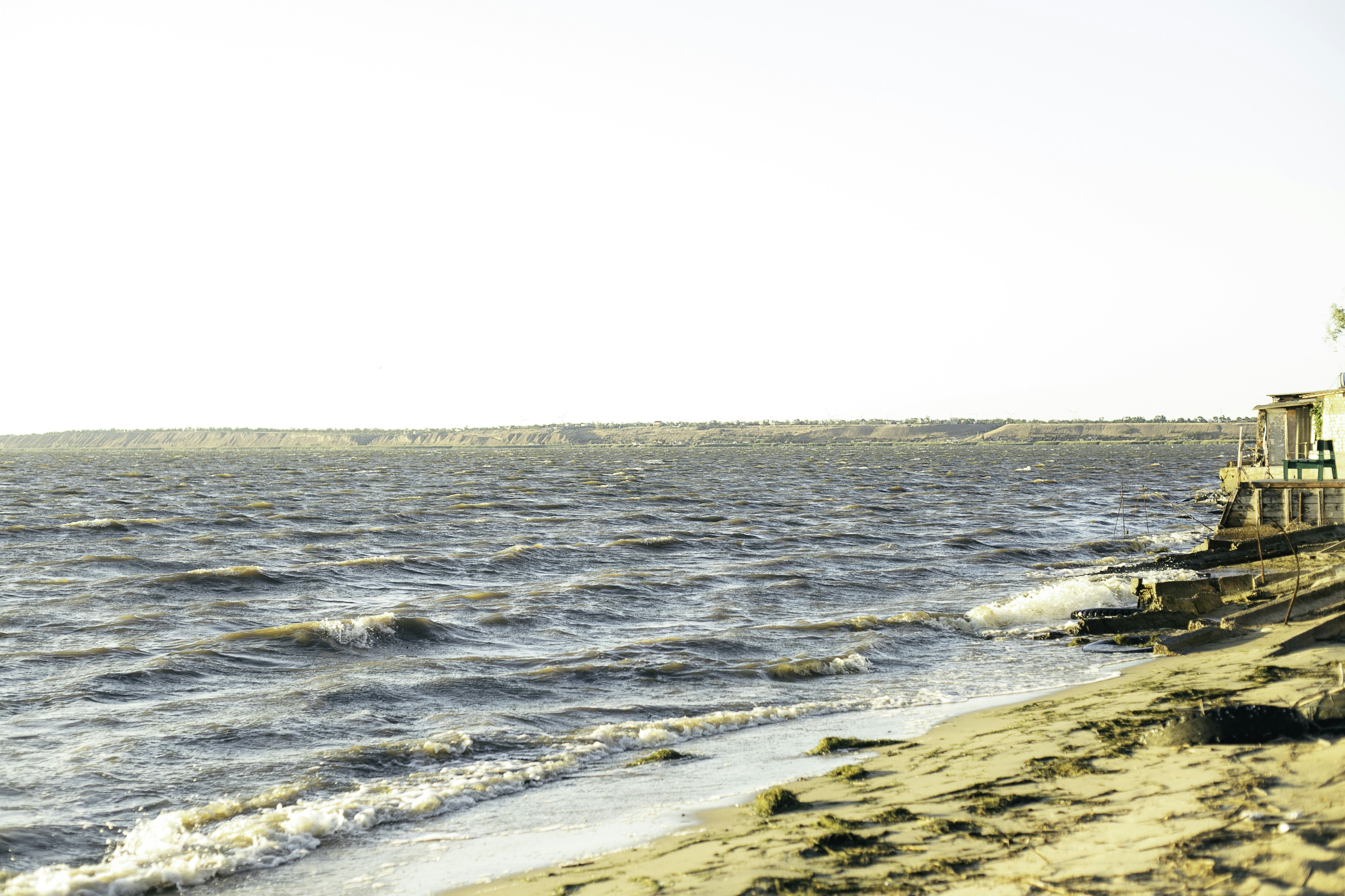 Le onde lambiscono la riva vicino a un piccolo edificio.