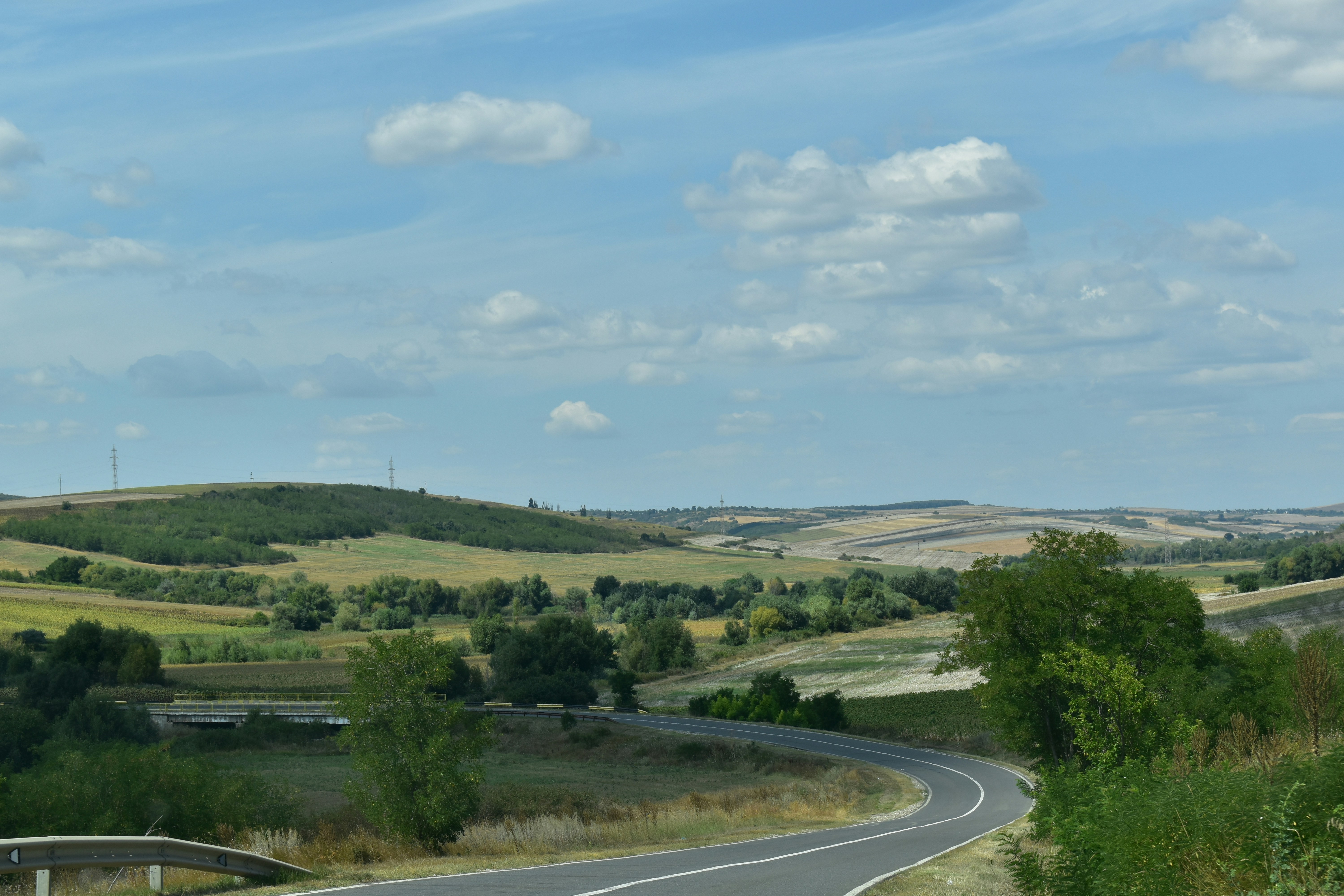 Curving road through rolling hills under a cloudy sky