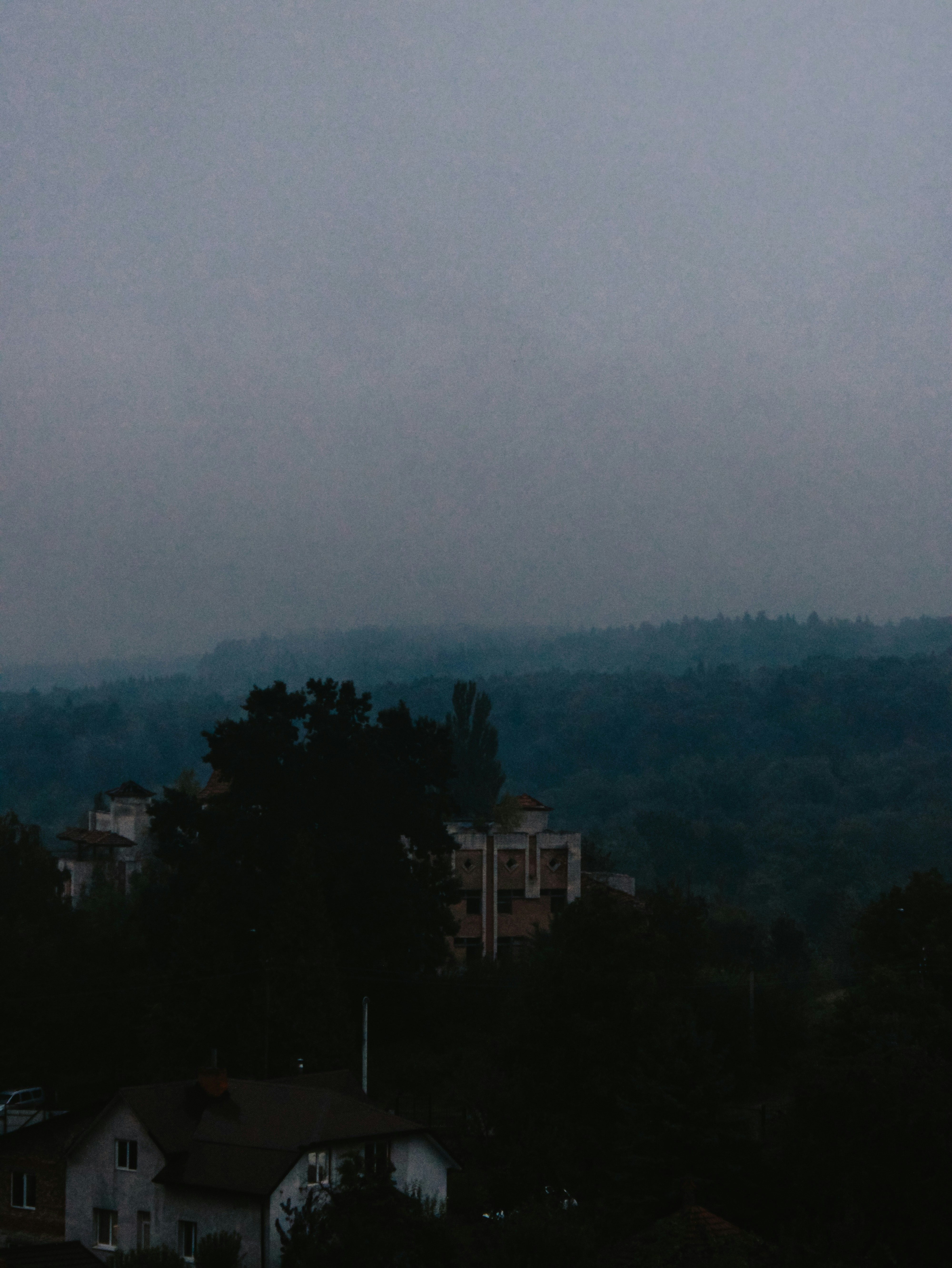 Misty hills with buildings and trees at dusk