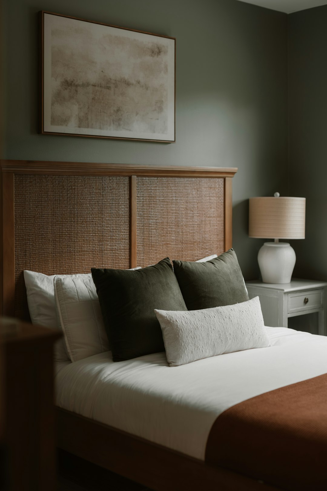 Wood headboard with white bedding and a warm table lamp