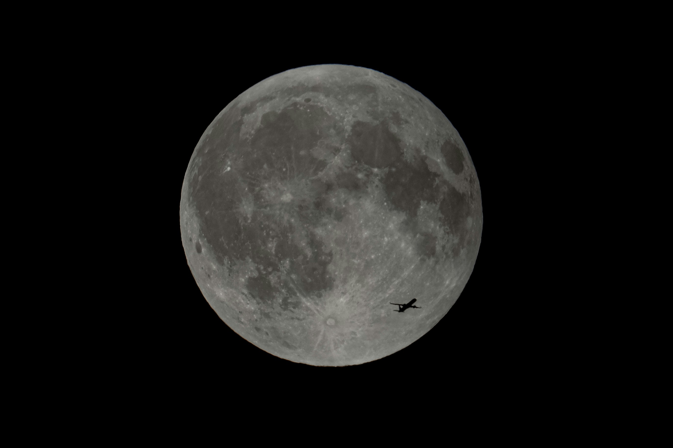 Full moon with a small airplane flying past.