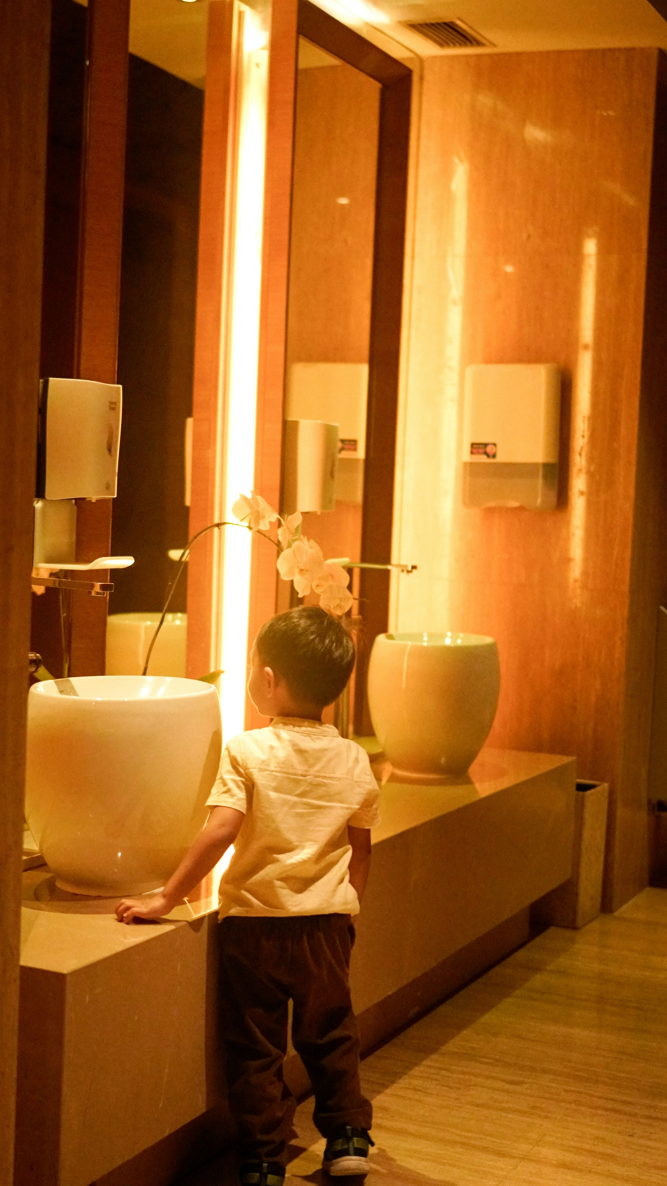 Young boy stands at a modern bathroom sink