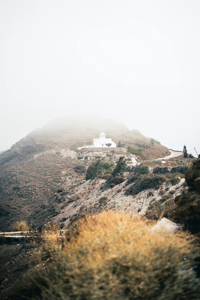Chapelle blanche dans la brume au sommet d'une montagne à Santorin