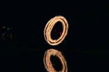 Fire dancer creates a glowing circle over water
