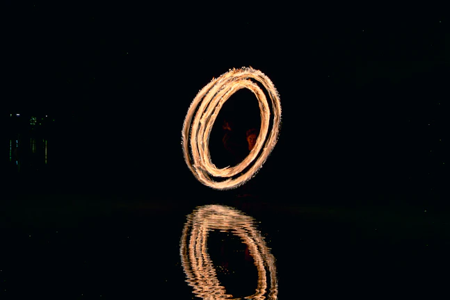 Fire dancer creates a glowing circle over water