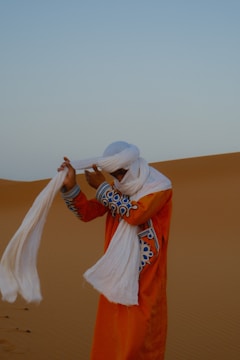 Man in traditional desert attire adjusting his turban