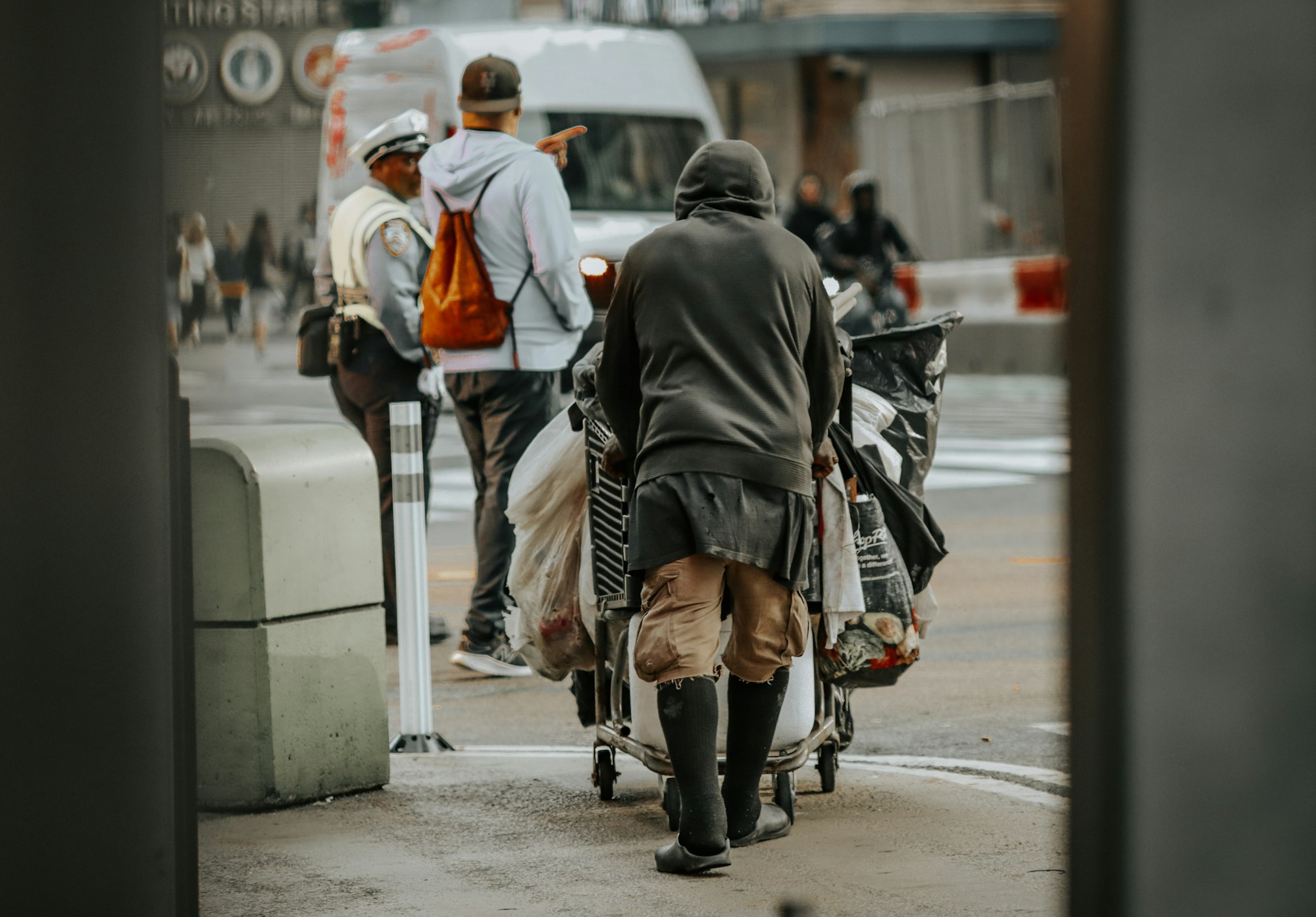 Person pushing cart with belongings on city street