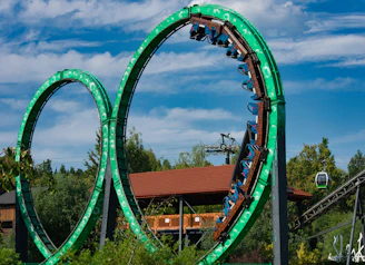 Roller coaster loops with riders against blue sky