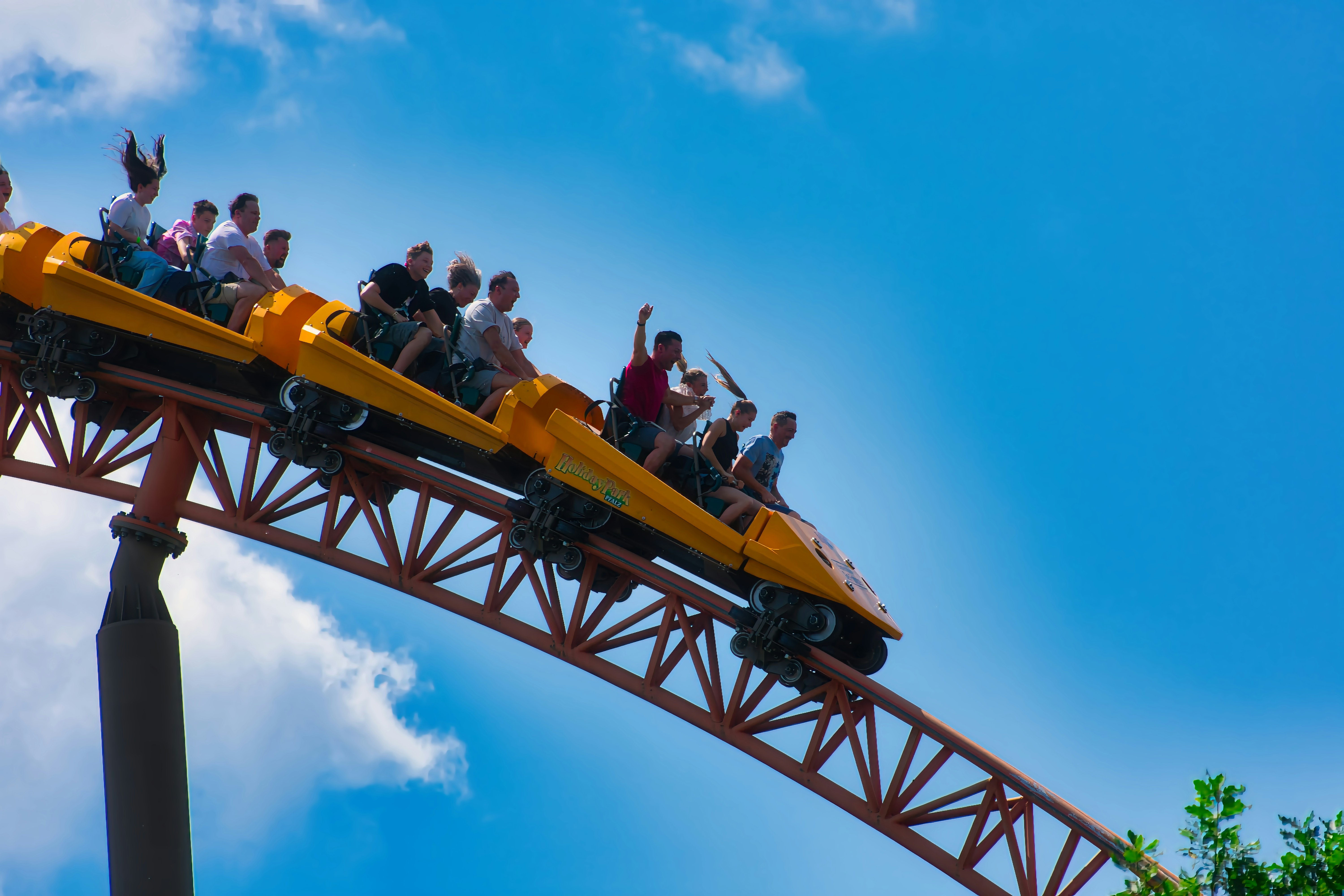 People riding a roller coaster on a sunny day.