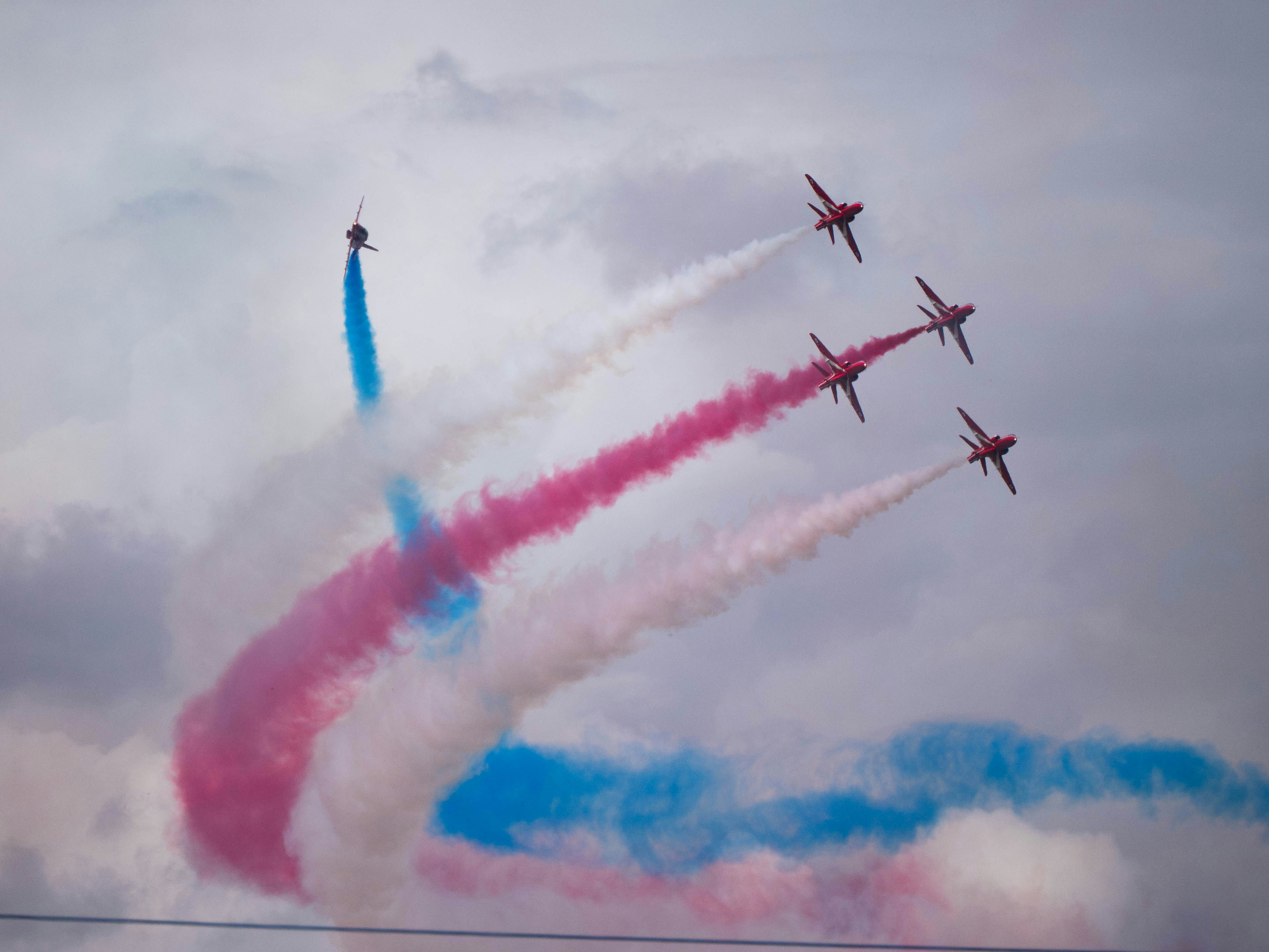 Red arrows perform aerobatics with colorful smoke trails.