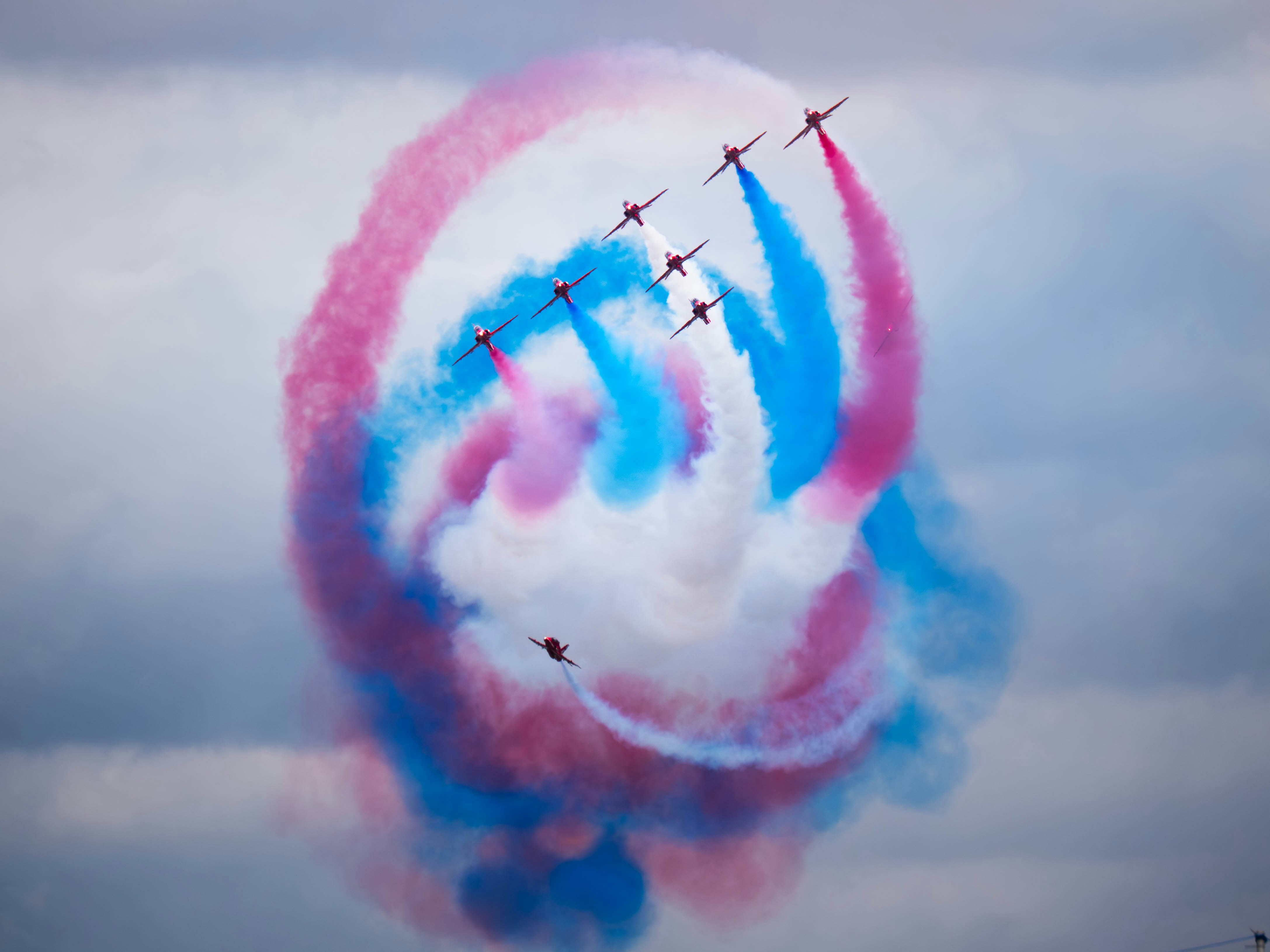 Planes create colorful smoke trails in the sky.