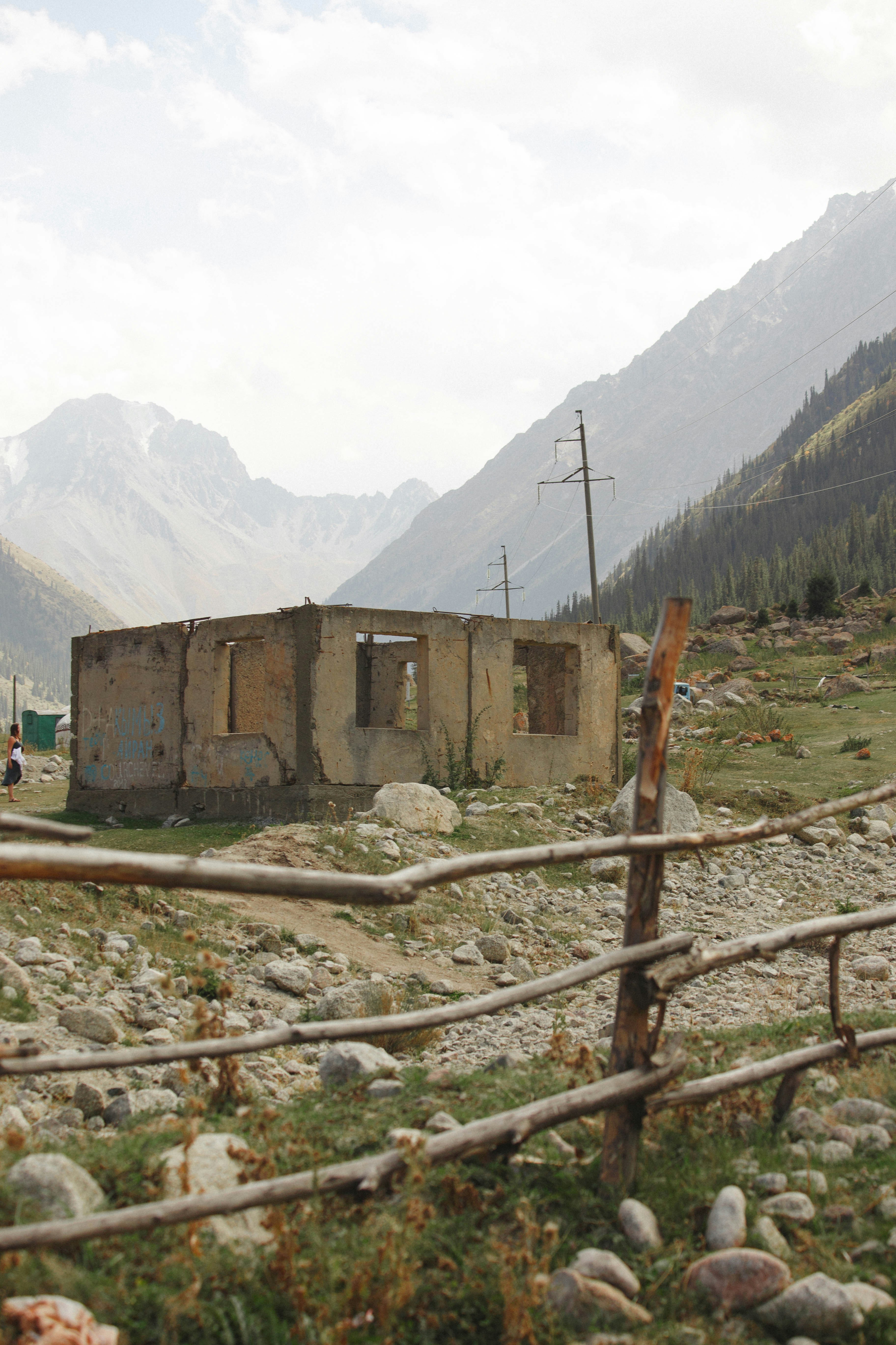 Ruined building in a mountainous landscape with wooden fence.