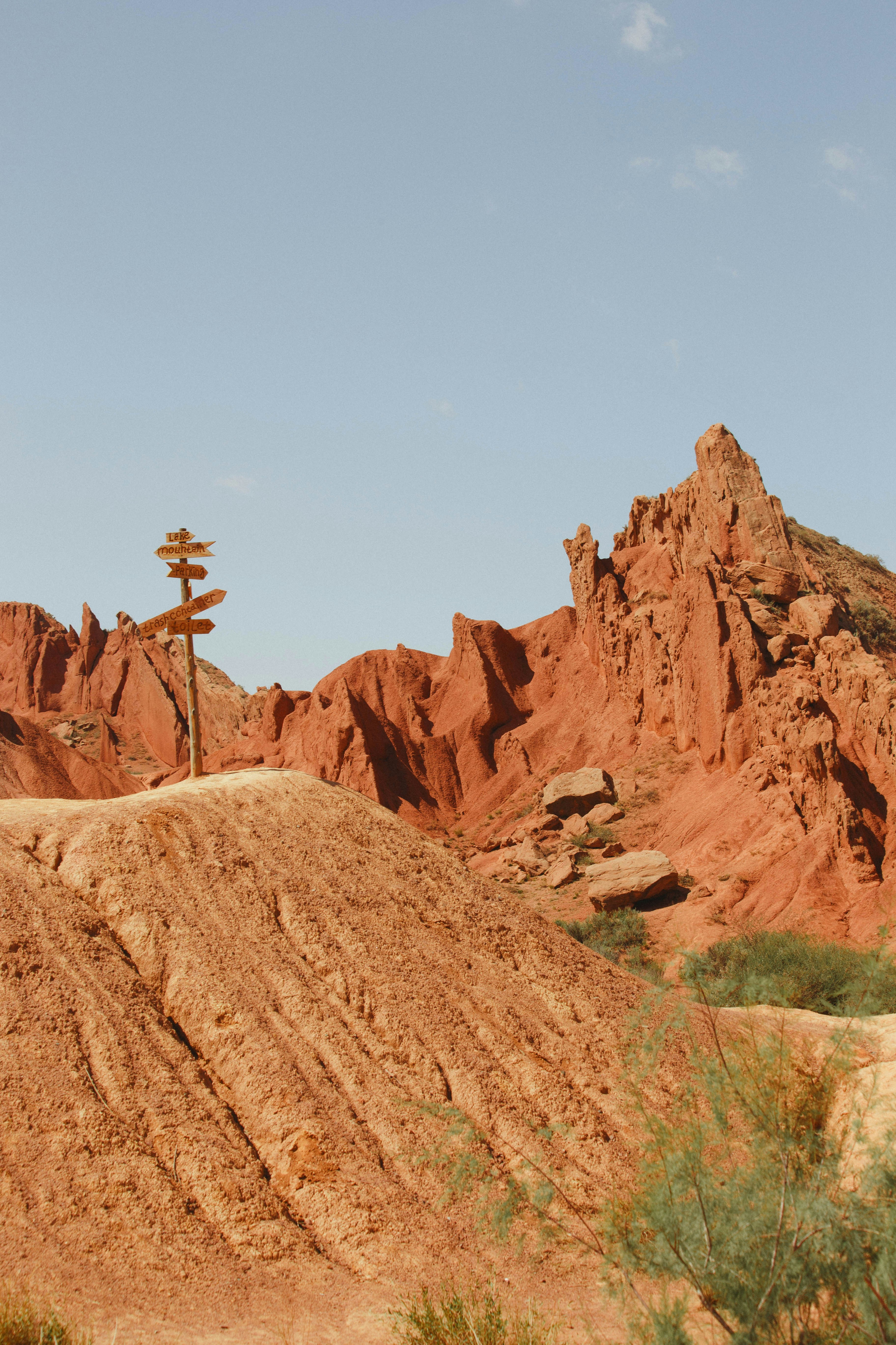 Wooden directional signpost in a red rock desert landscape.