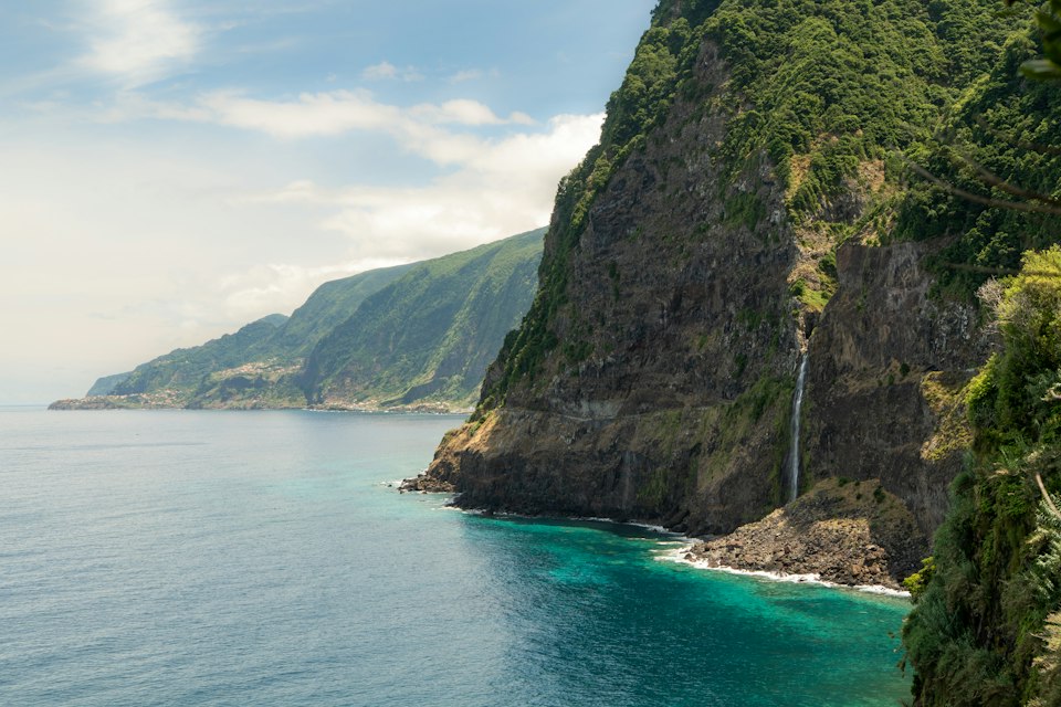 Dramatic coastal cliffs with a waterfall cascading into the Atlantic, Madeira