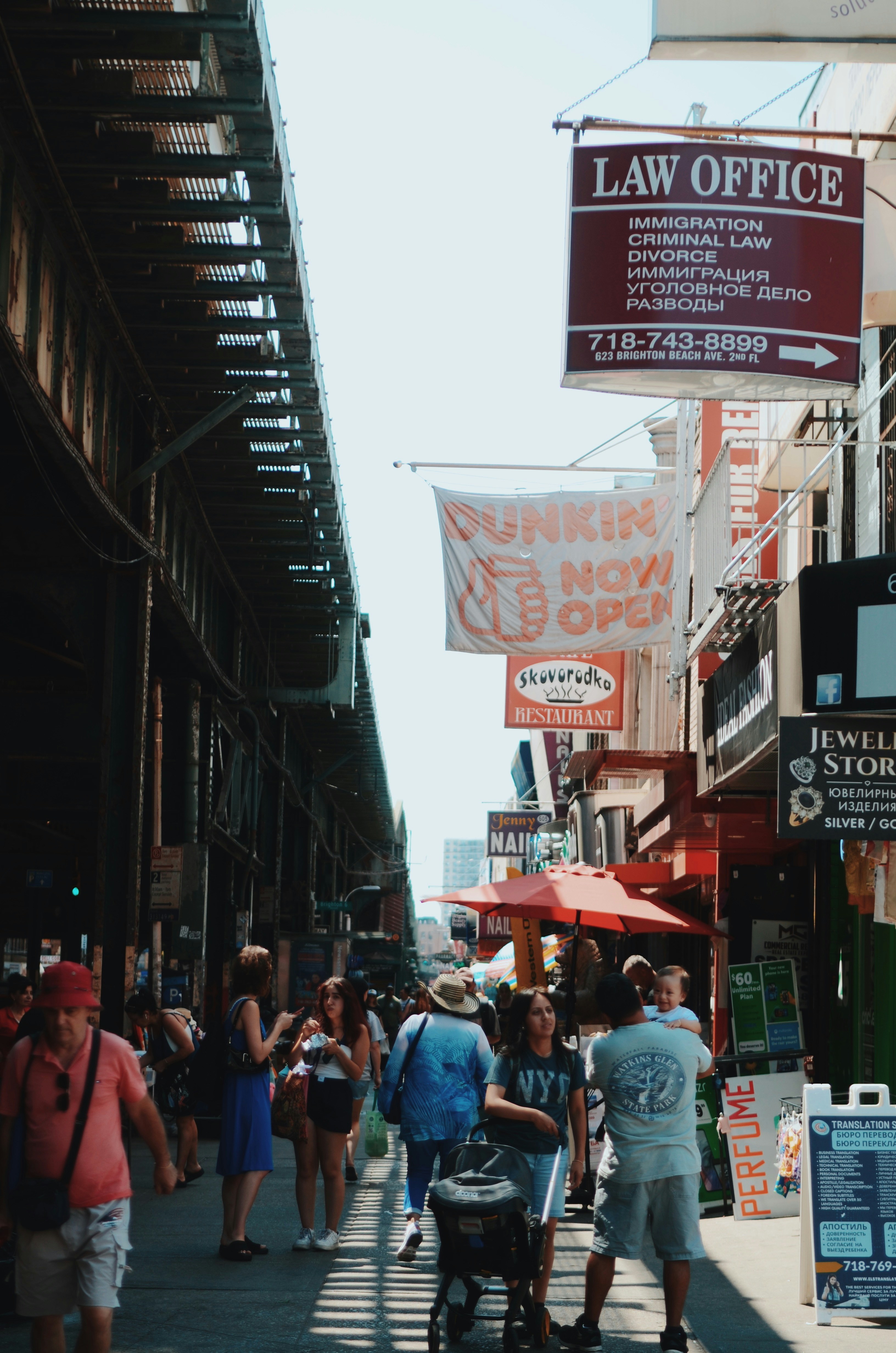 Die Menschen spazieren entlang einer sonnigen Straße mit Geschäften und Geschäften.