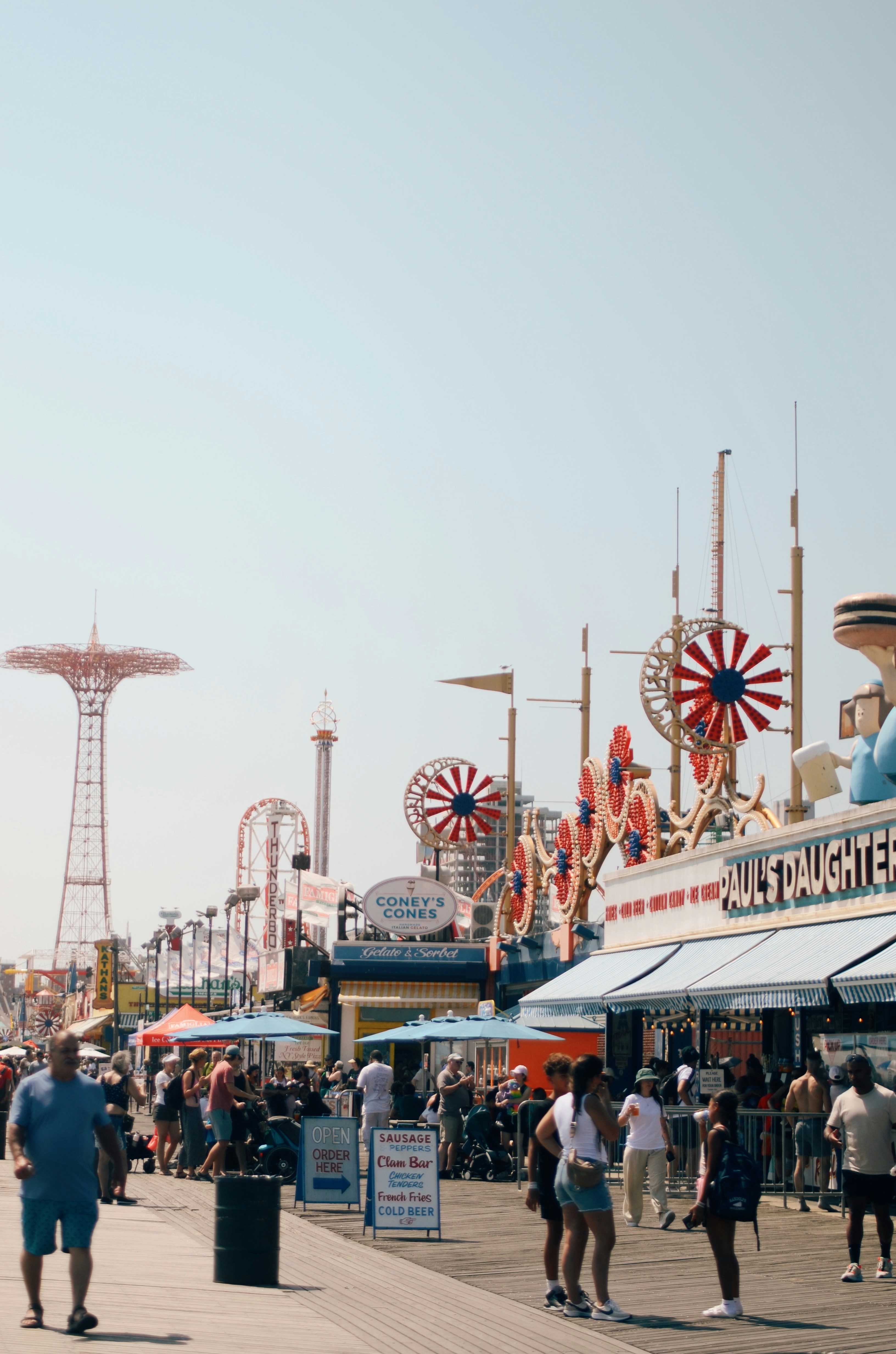 Die Menschen schlendern entlang einer Promenade mit Fahrgeschäften in Vergnügungsparks.