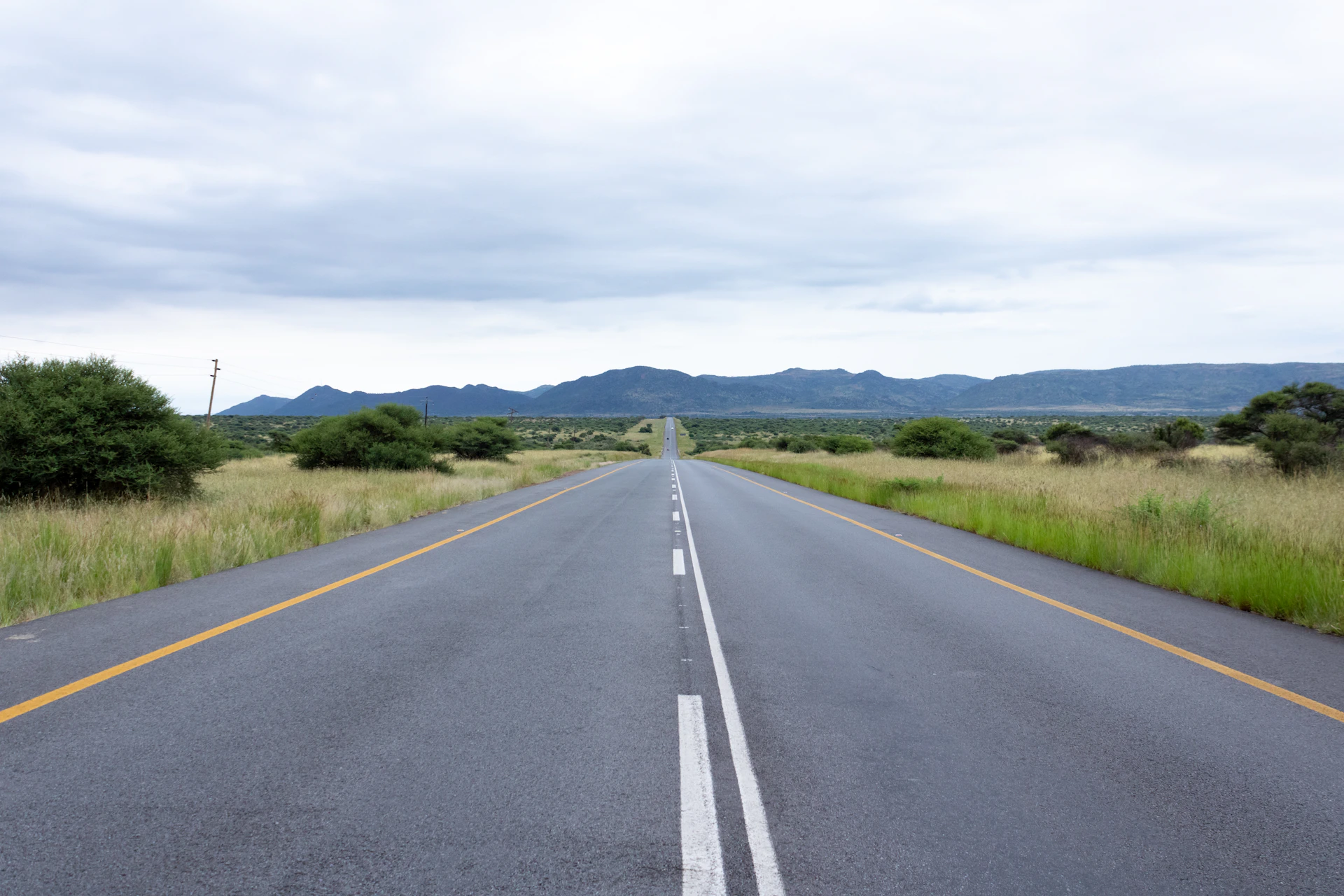 An empty asphalt road stretching towards distant mountains