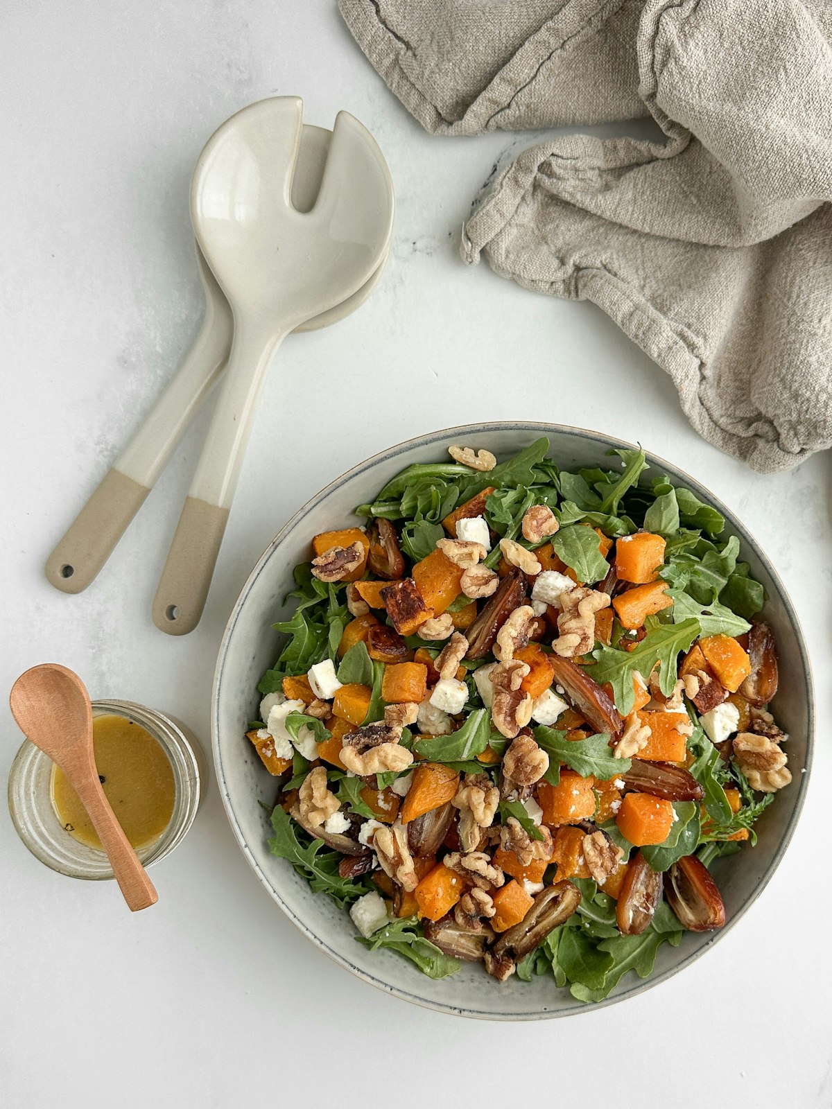 Fresh arugula salad with shaved cheese and nuts in a ceramic bowl on a wooden table
