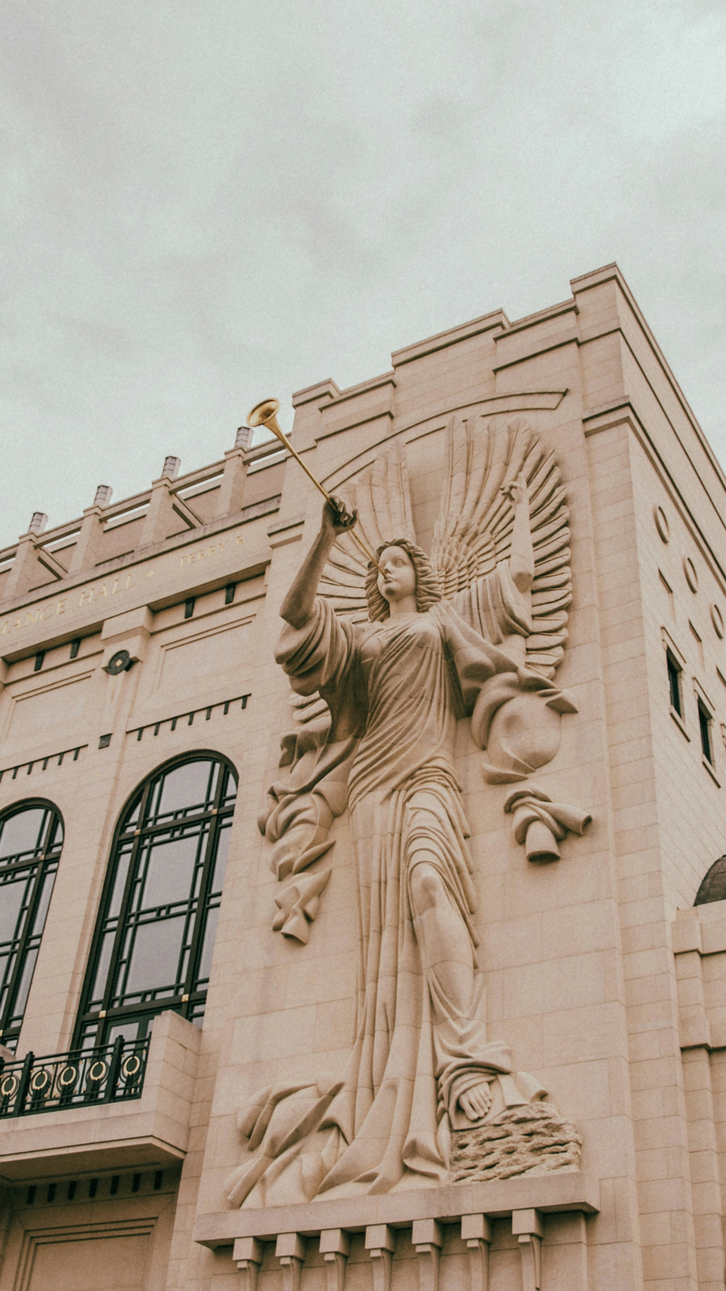 Stone angel statue with trumpet on building facade