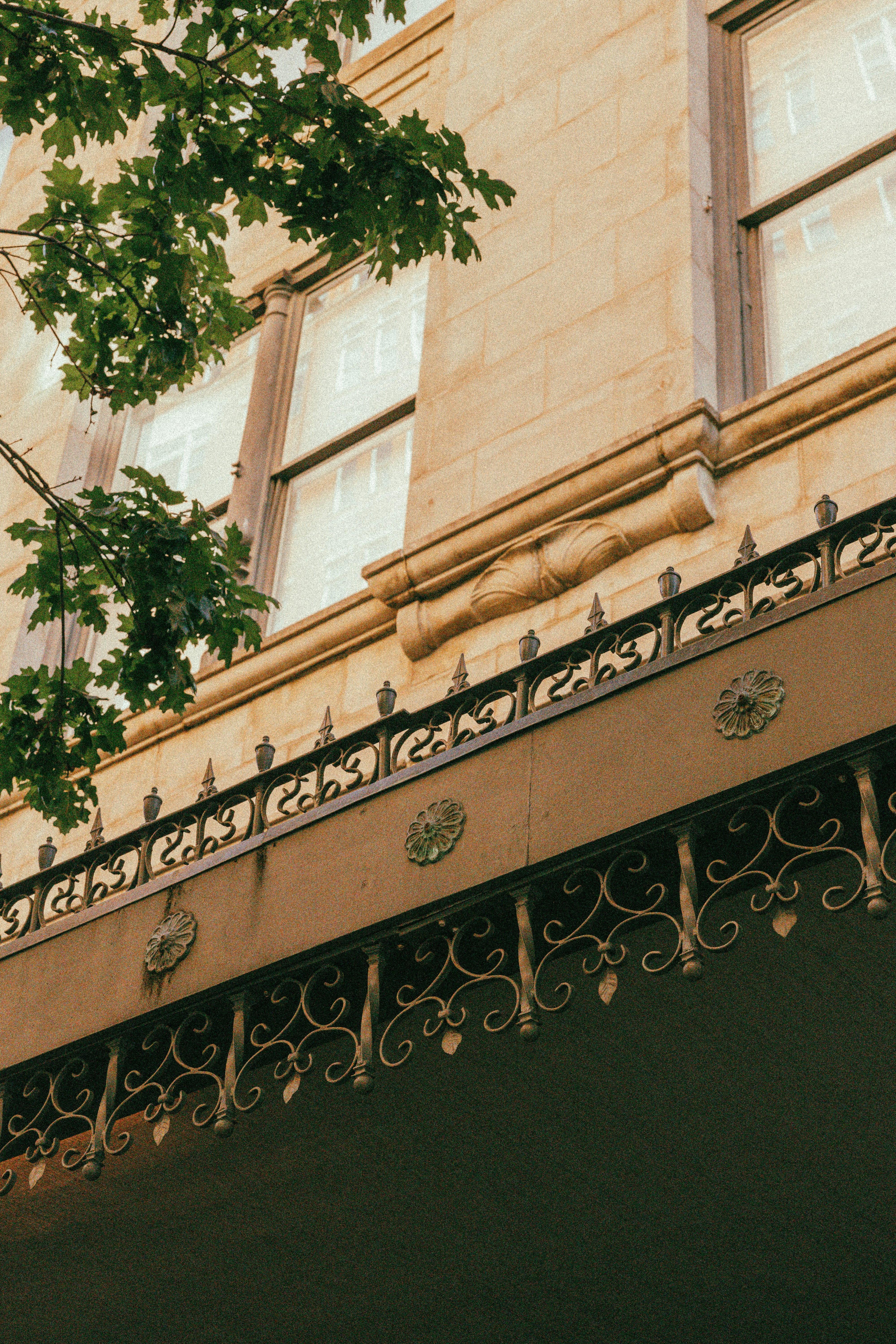 Trabalhos em metal ornamentados adornam a fachada de um edifício com janelas.