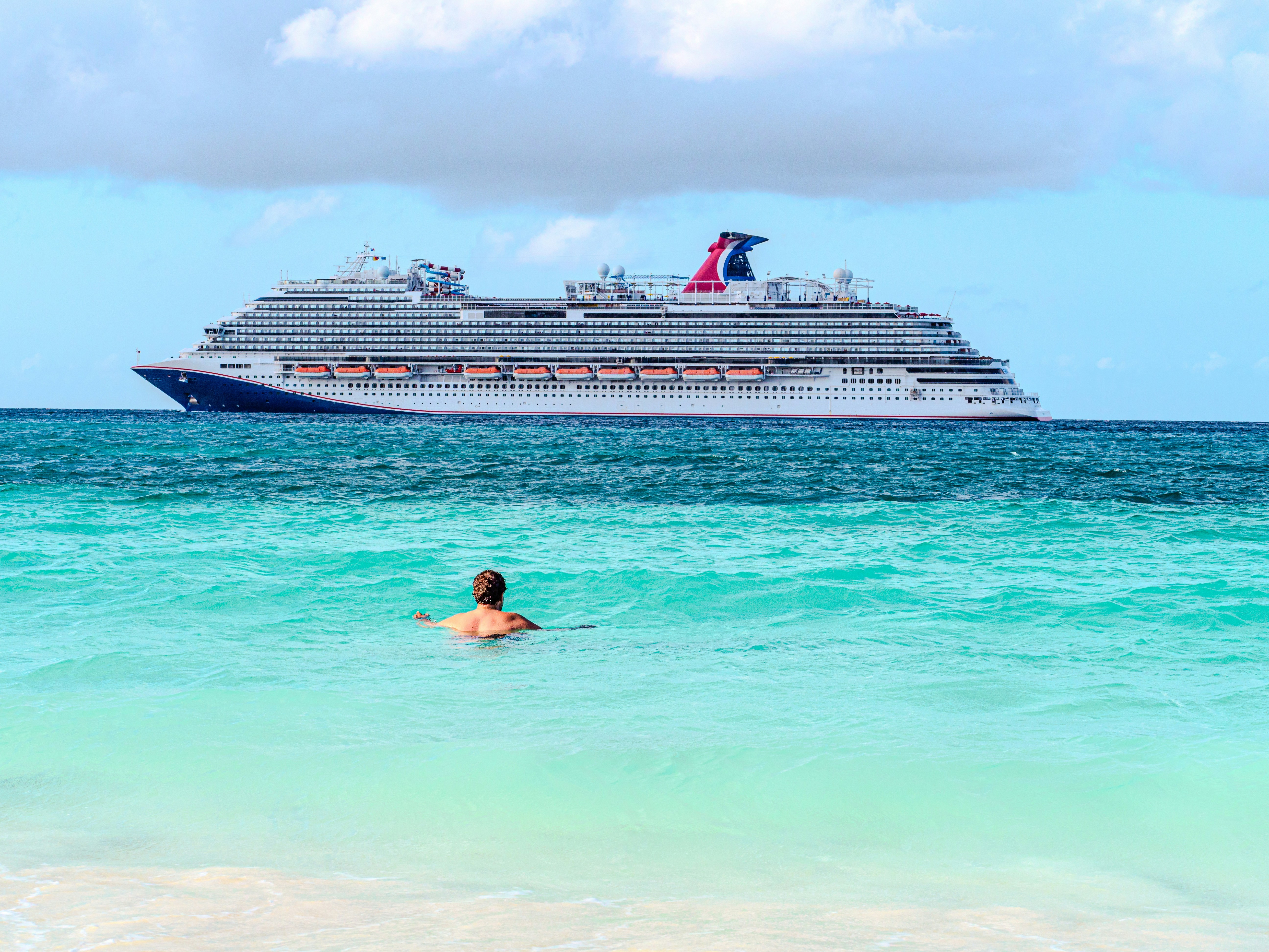 Person swimming in ocean with cruise ship in distance