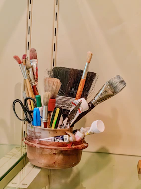 Assortment of art brushes and tools in a container.