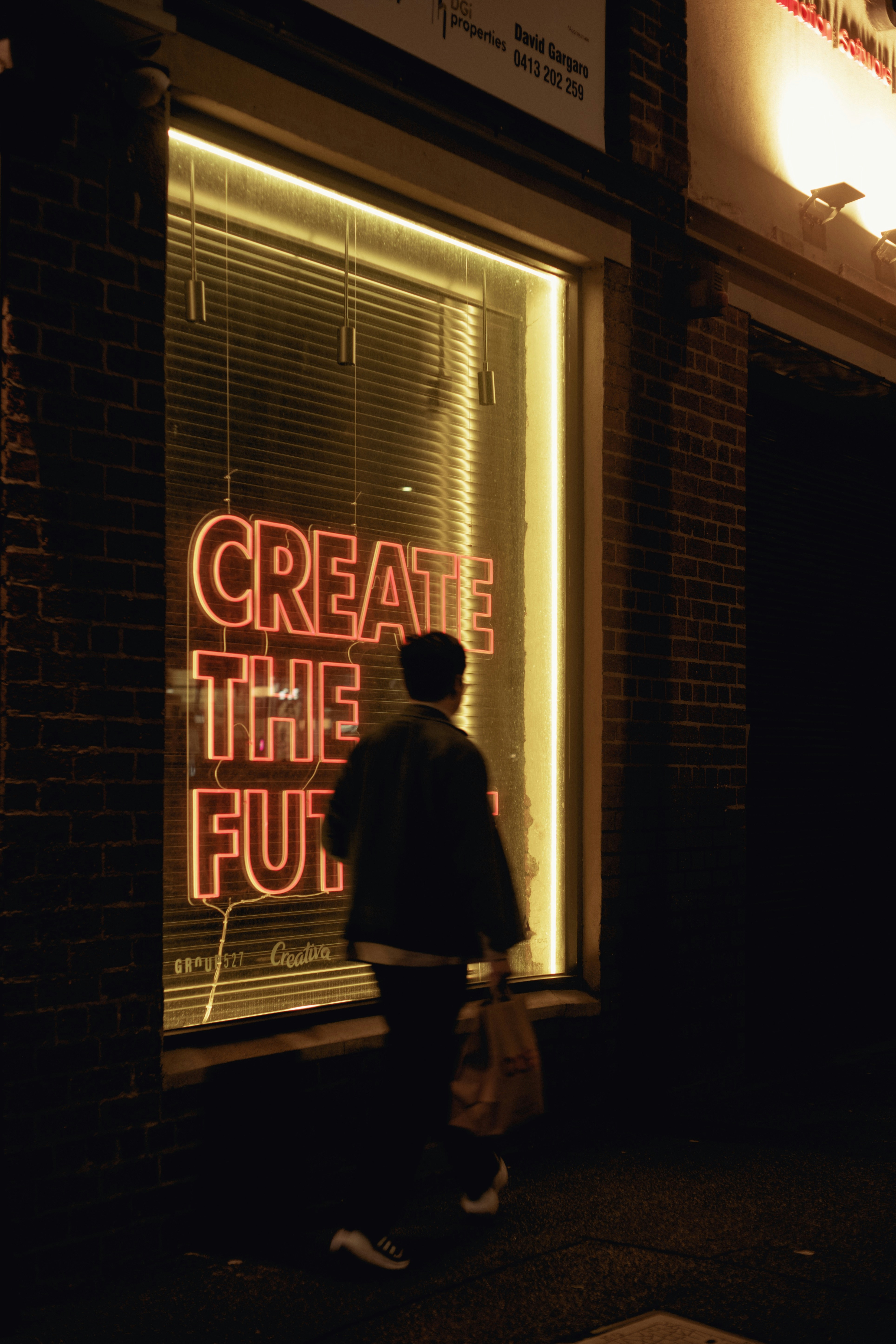Person walks towards neon sign in window at night