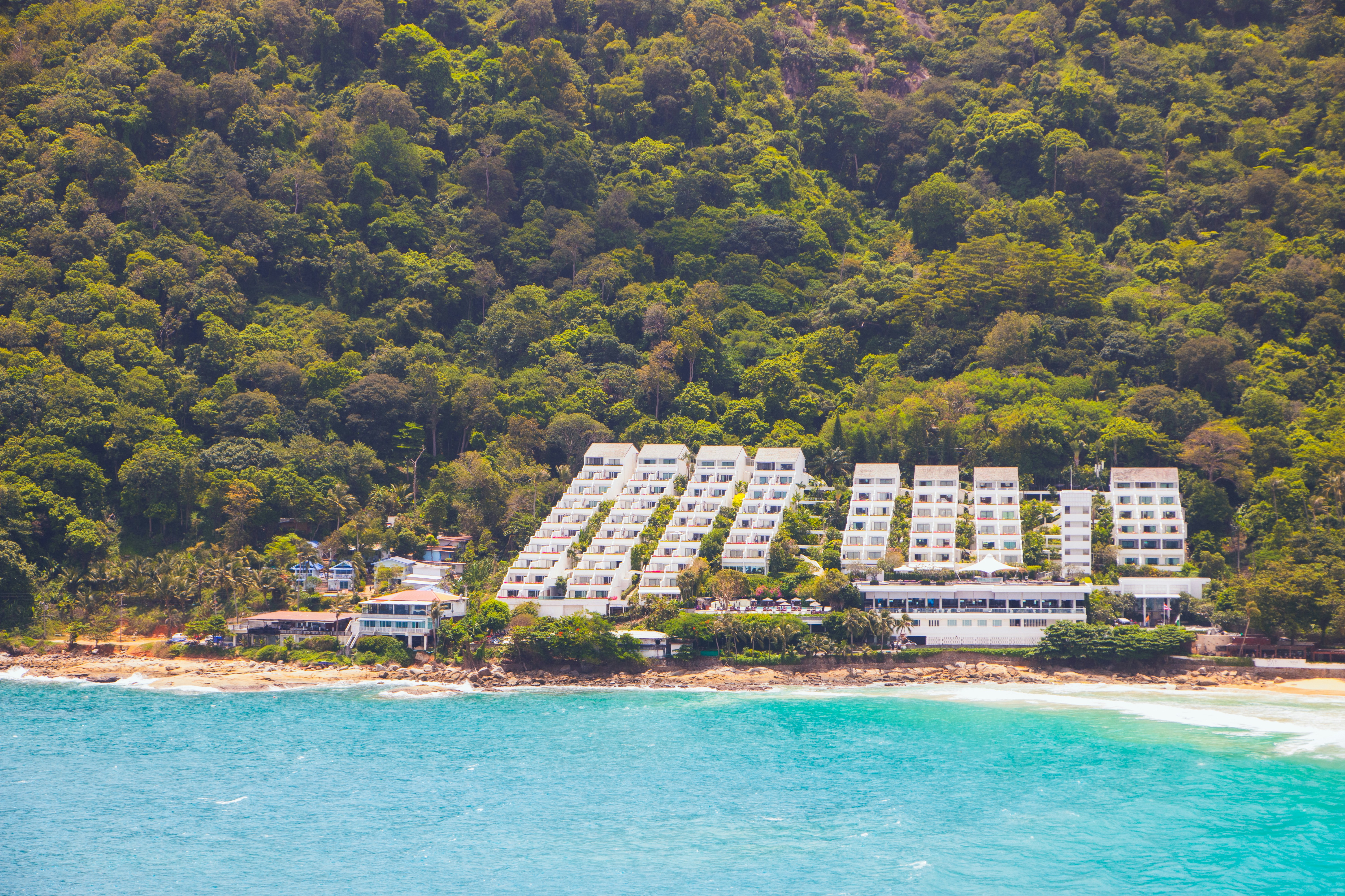 Resort buildings nestled at the base of a lush green hill.
