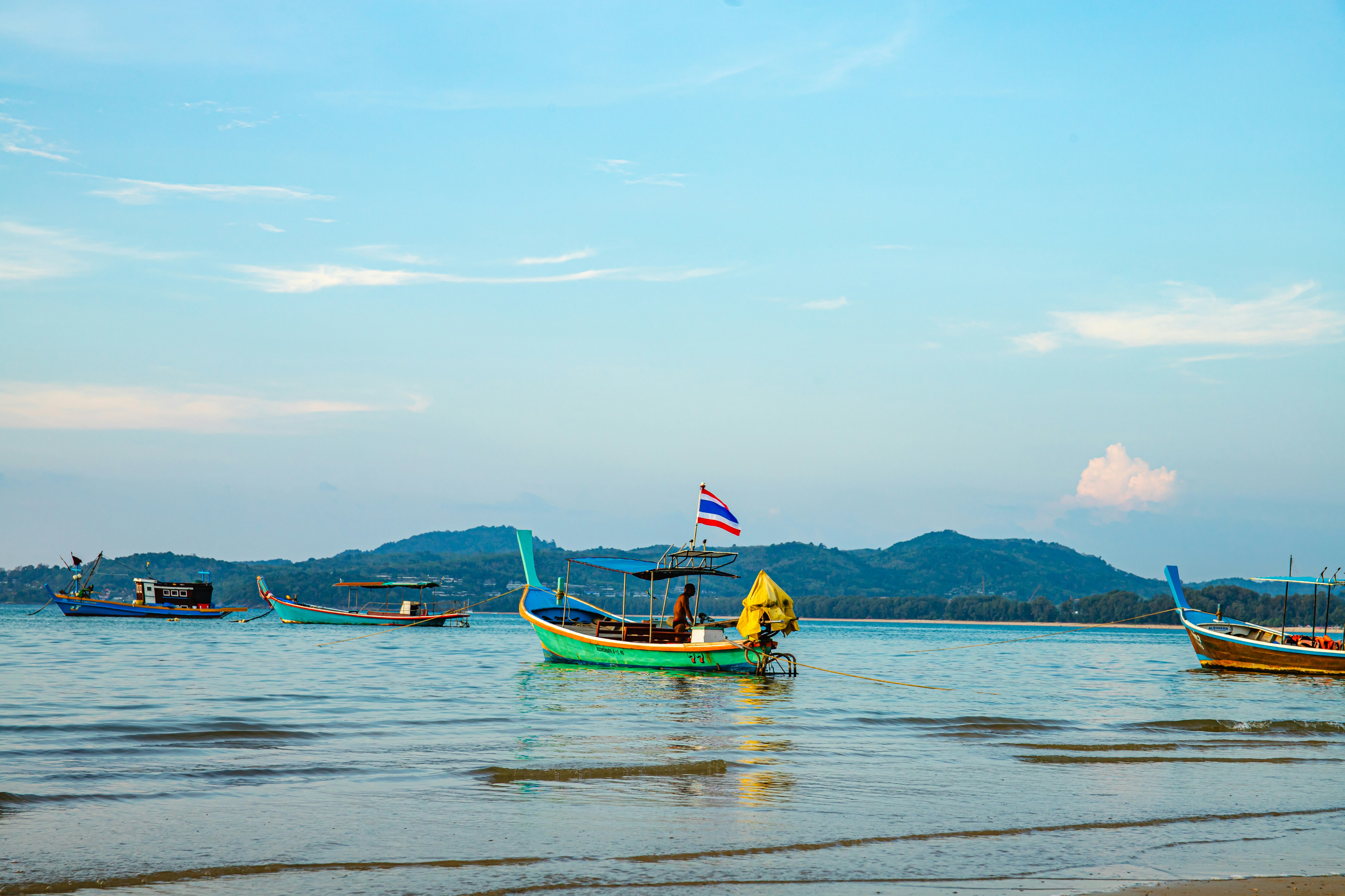 Several boats float on calm water near a distant shore.