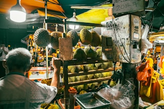 Man shopping for durian fruit at a market stall.