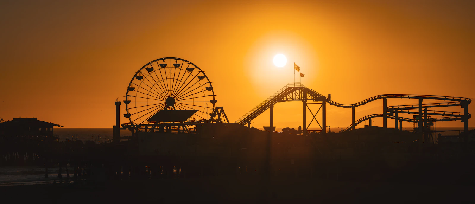 Amusement park rides silhouetted against a vibrant sunset