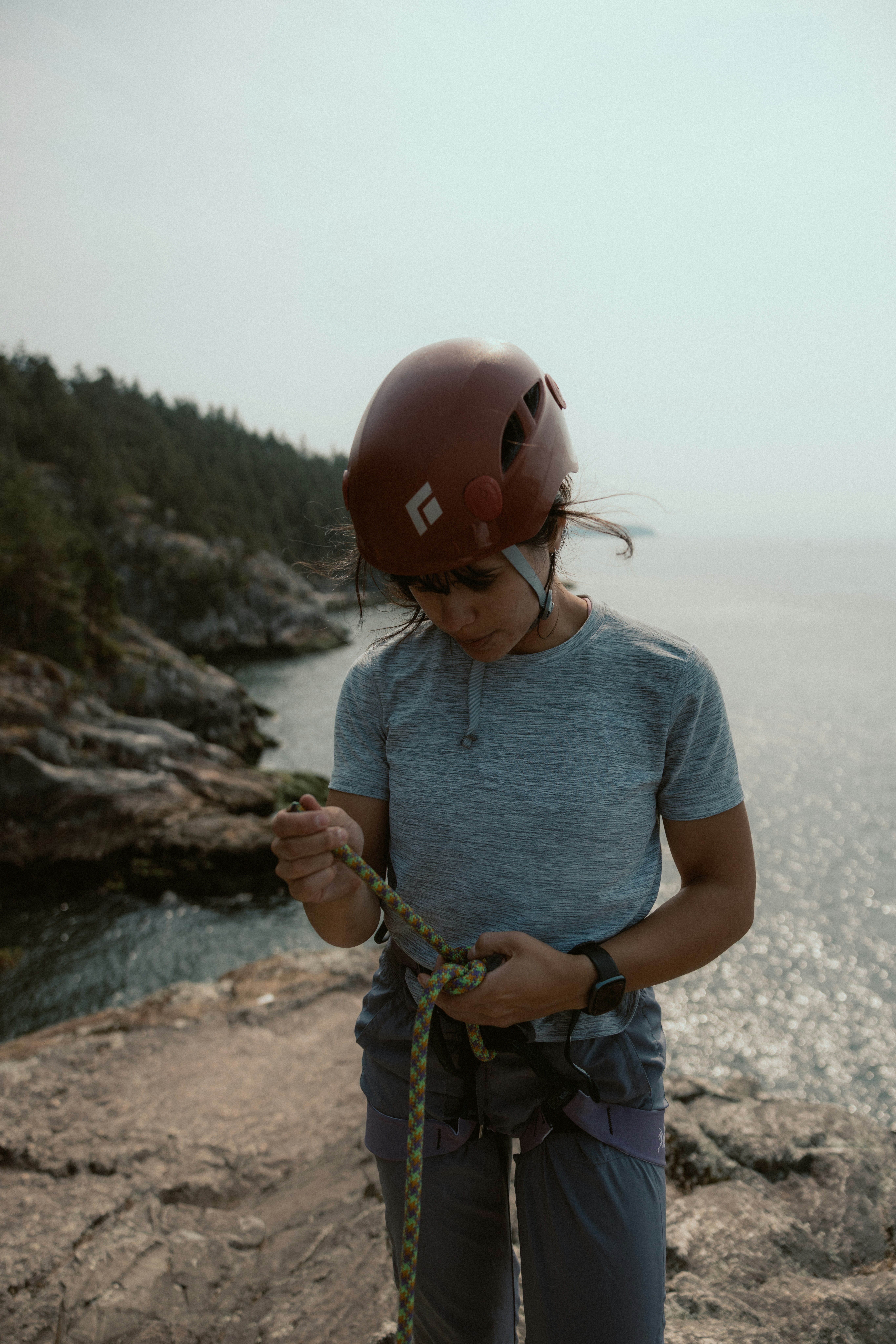 Person in helmet tying climbing rope near water