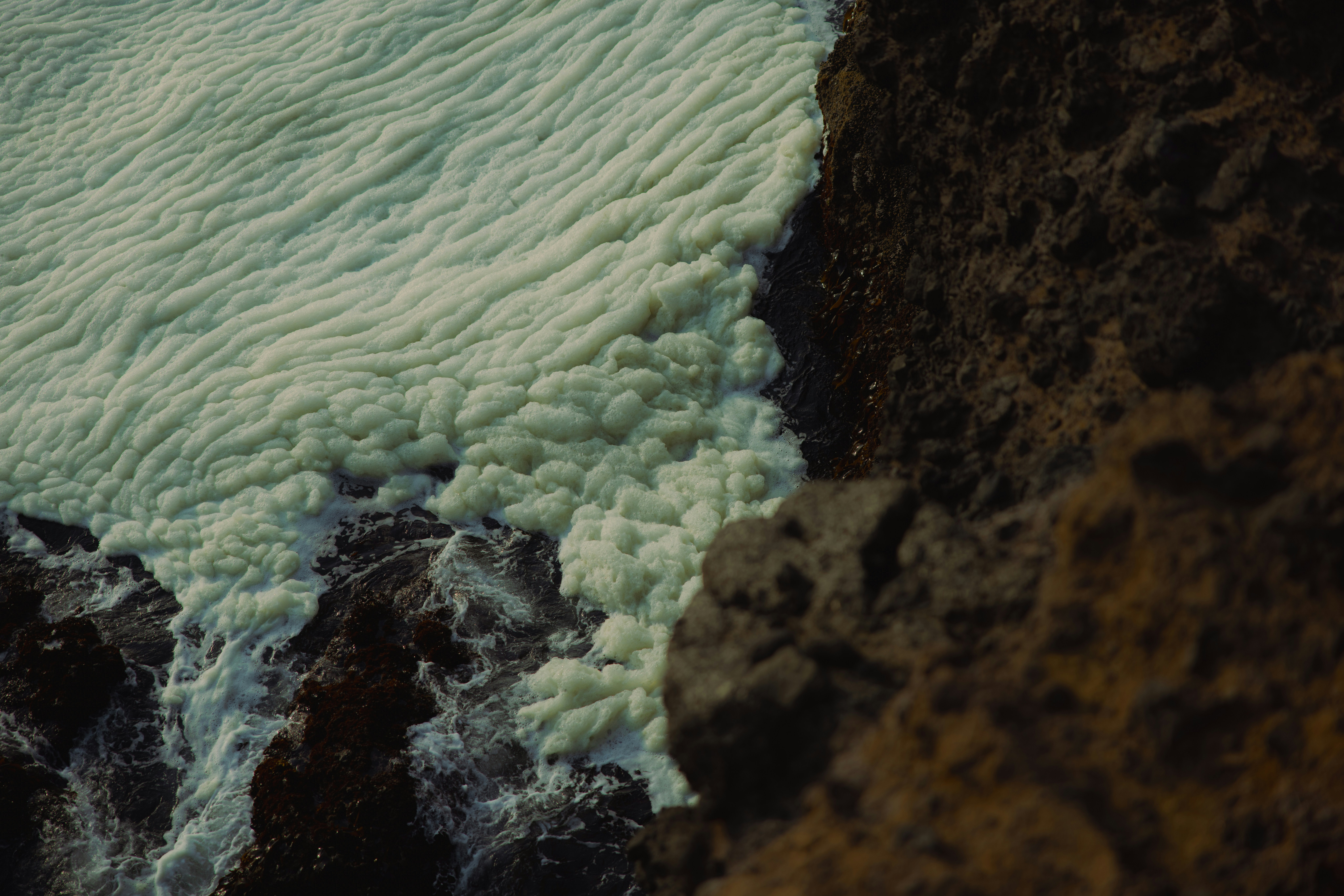 Foamy water meets rocky shore from above