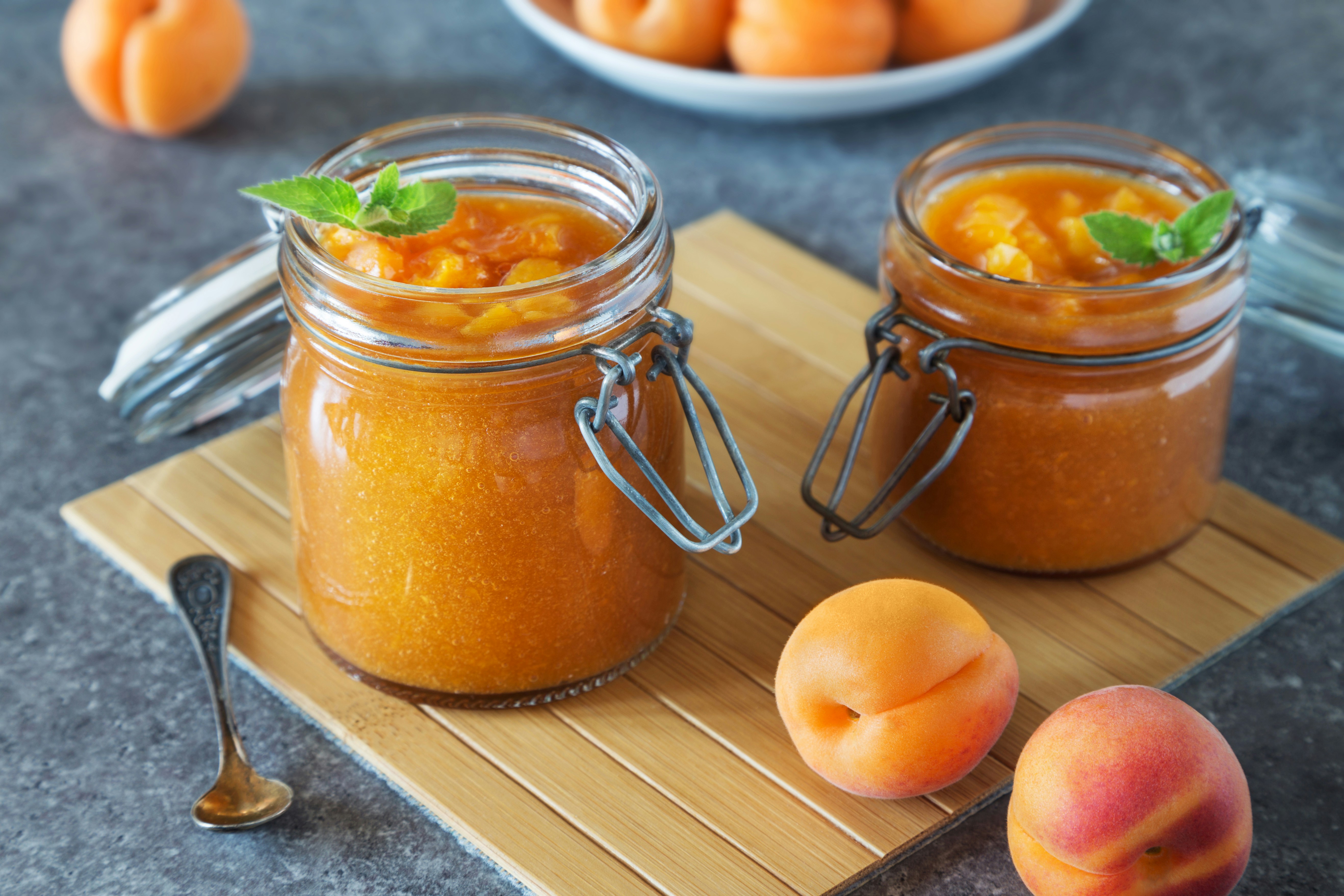 Two jars of apricot jam with fresh apricots