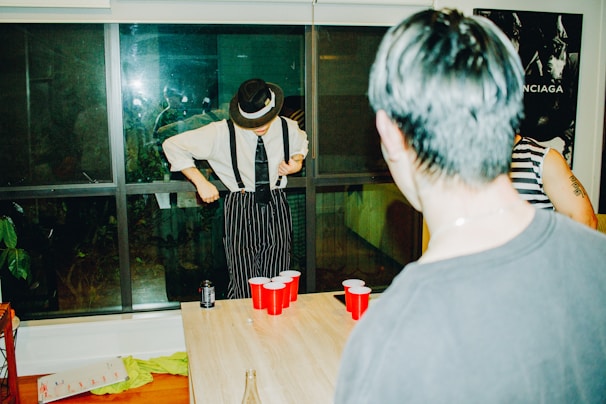 People playing beer pong indoors at night.