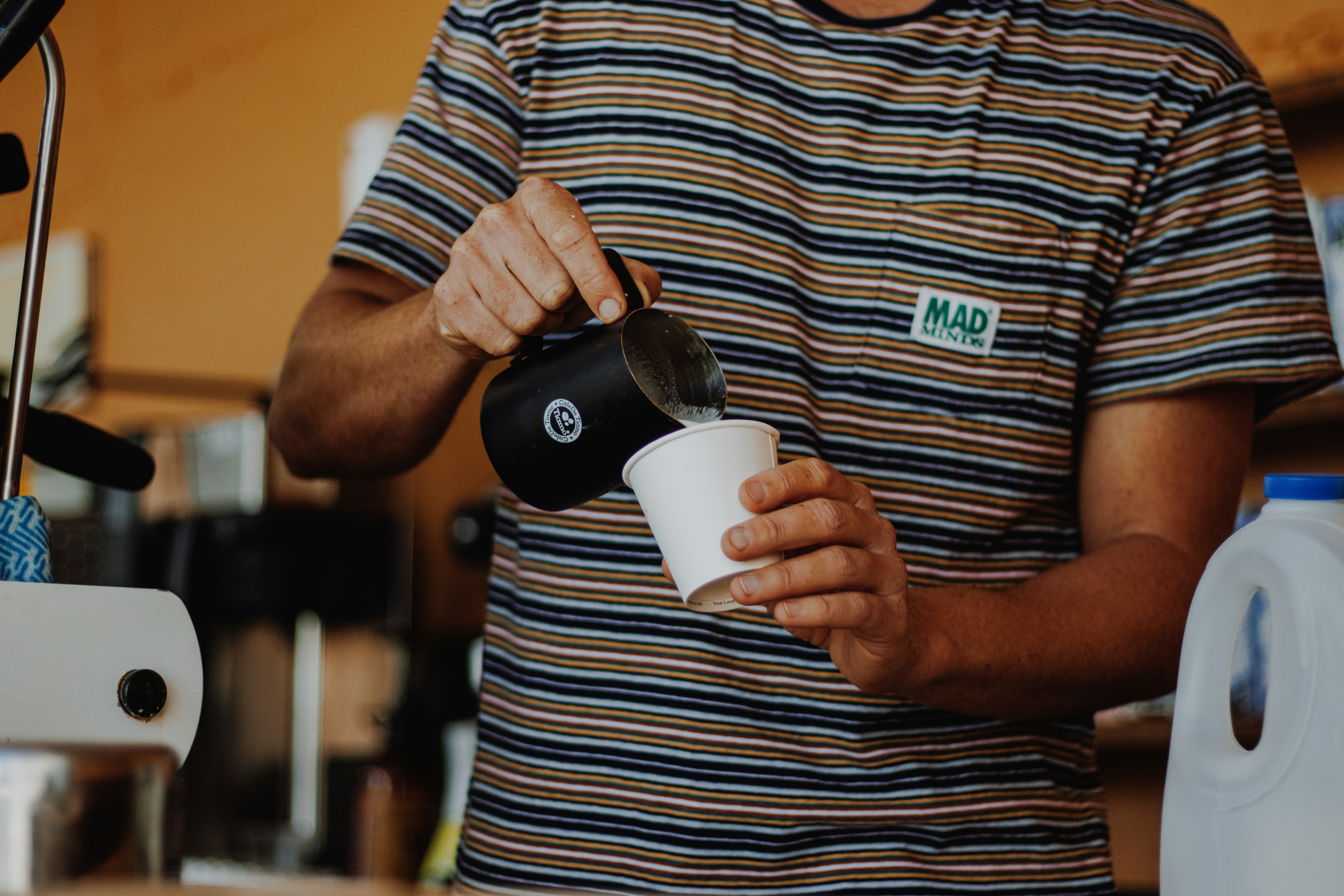 Barista pouring milk into a small cup