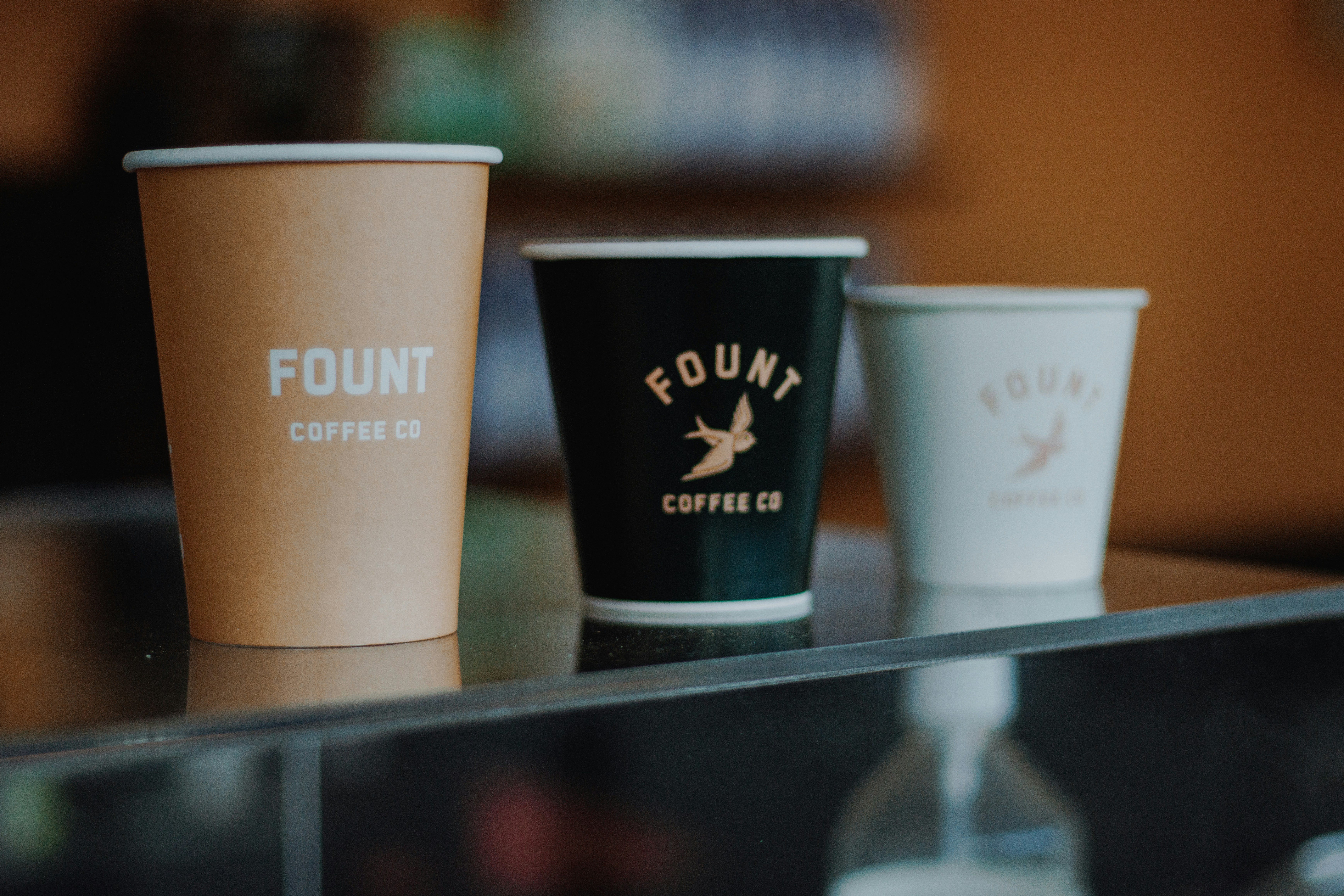 Drei Kaffeetassen mit Fount Coffee Co. Branding.
