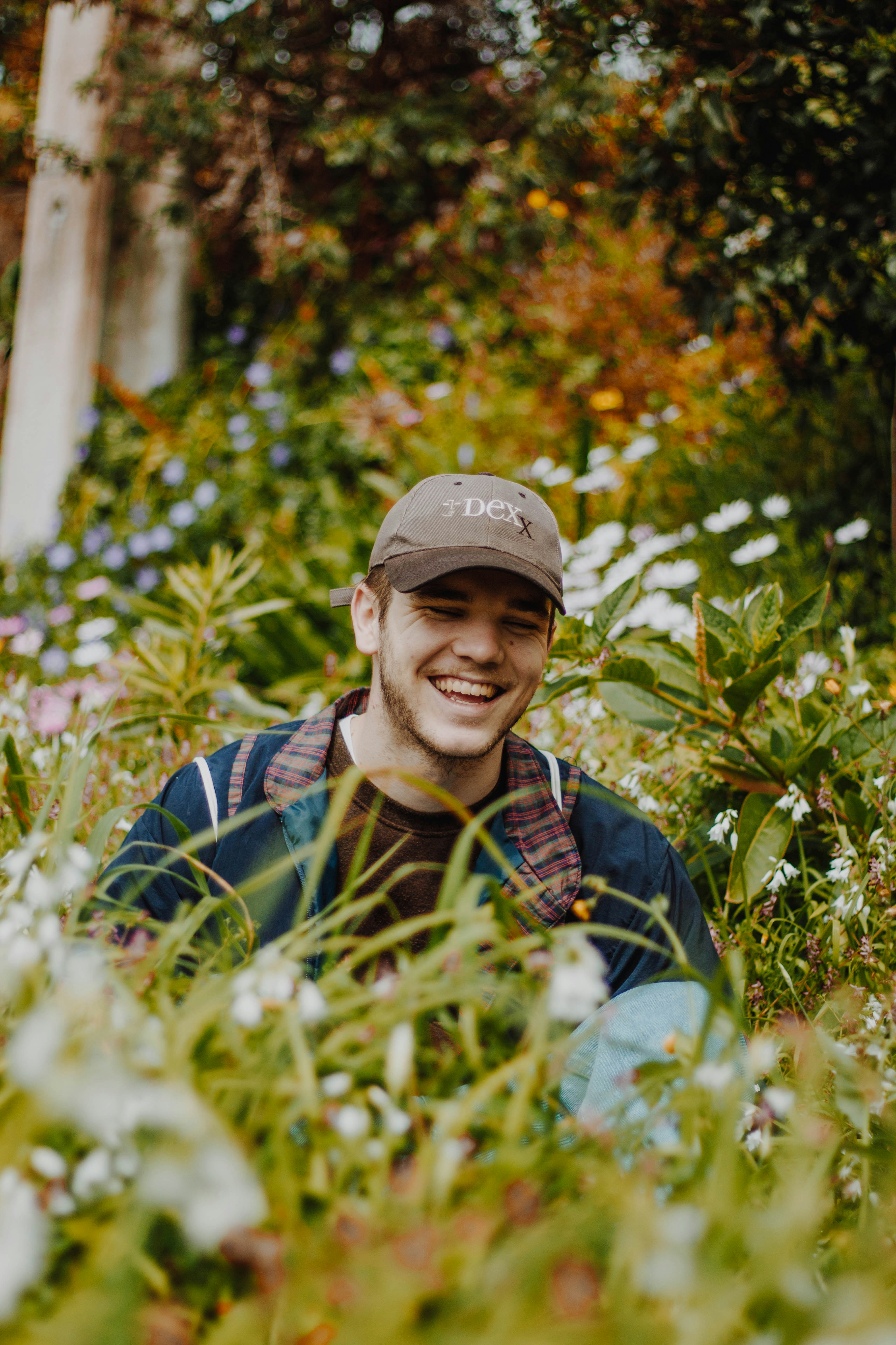 Man smiling while sitting in a field of flowers.